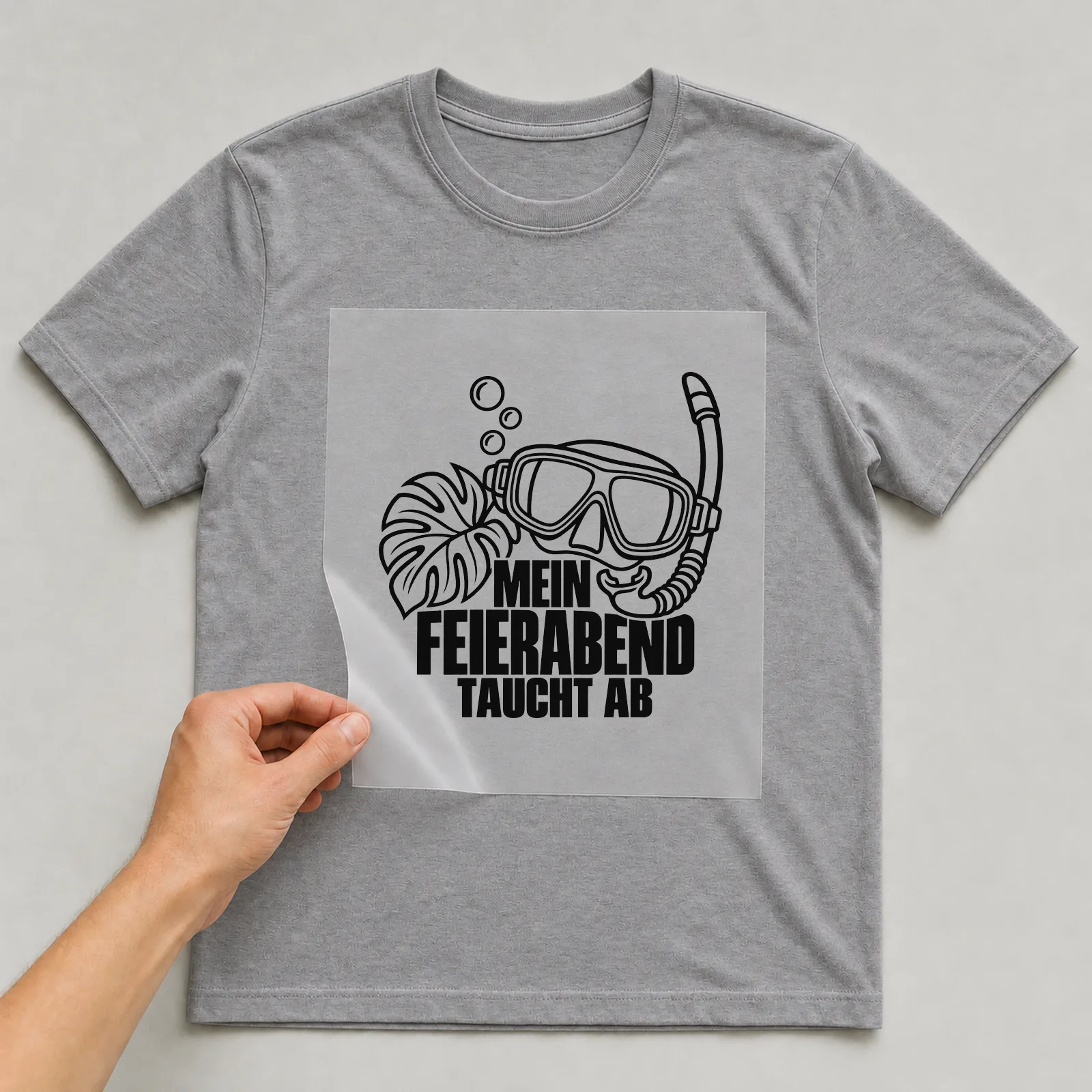 Bügelbild „Mein Feierabend taucht ab“ auf grauem T-Shirt, Folie wird aufgelegt