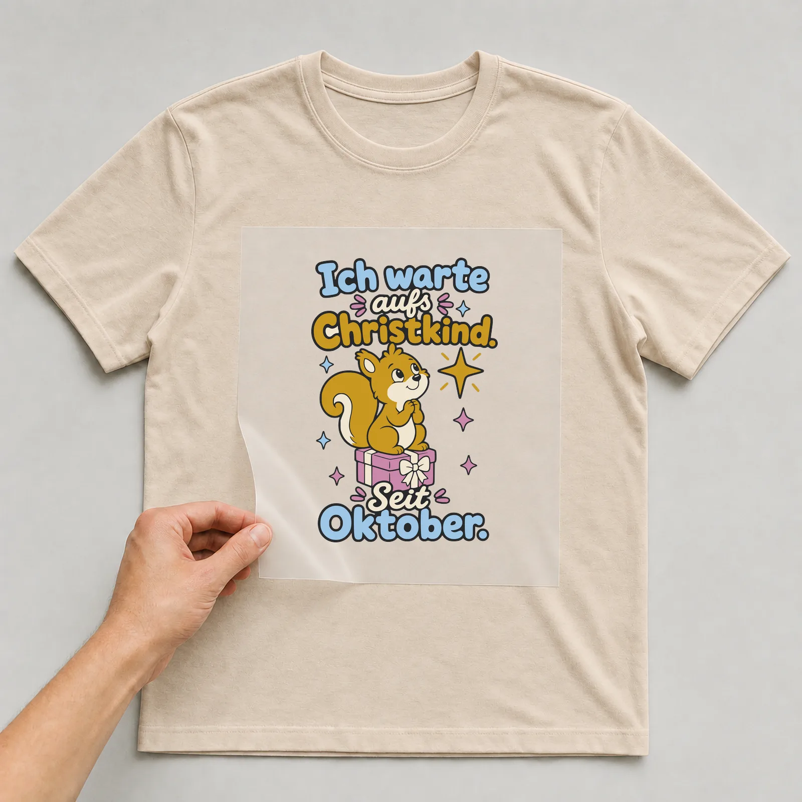 Bügelbild Ich warte aufs Christkind. Seit Oktober. auf beigem T-Shirt, Folie wird aufgelegt