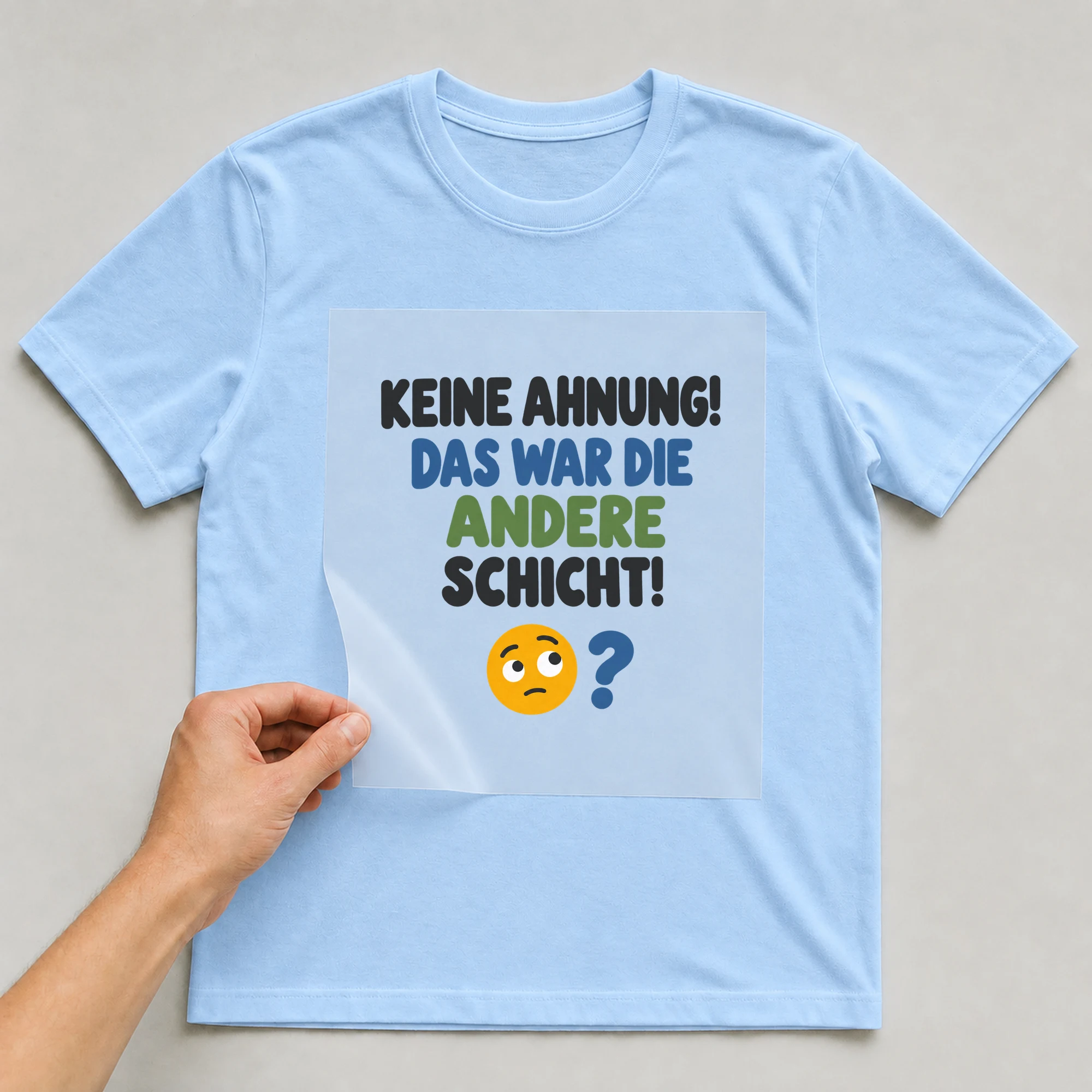 Bügelbild „KEINE AHNUNG! DAS WAR DIE ANDERE SCHICHT!“ auf babyblauem T-Shirt, Folie wird aufgelegt