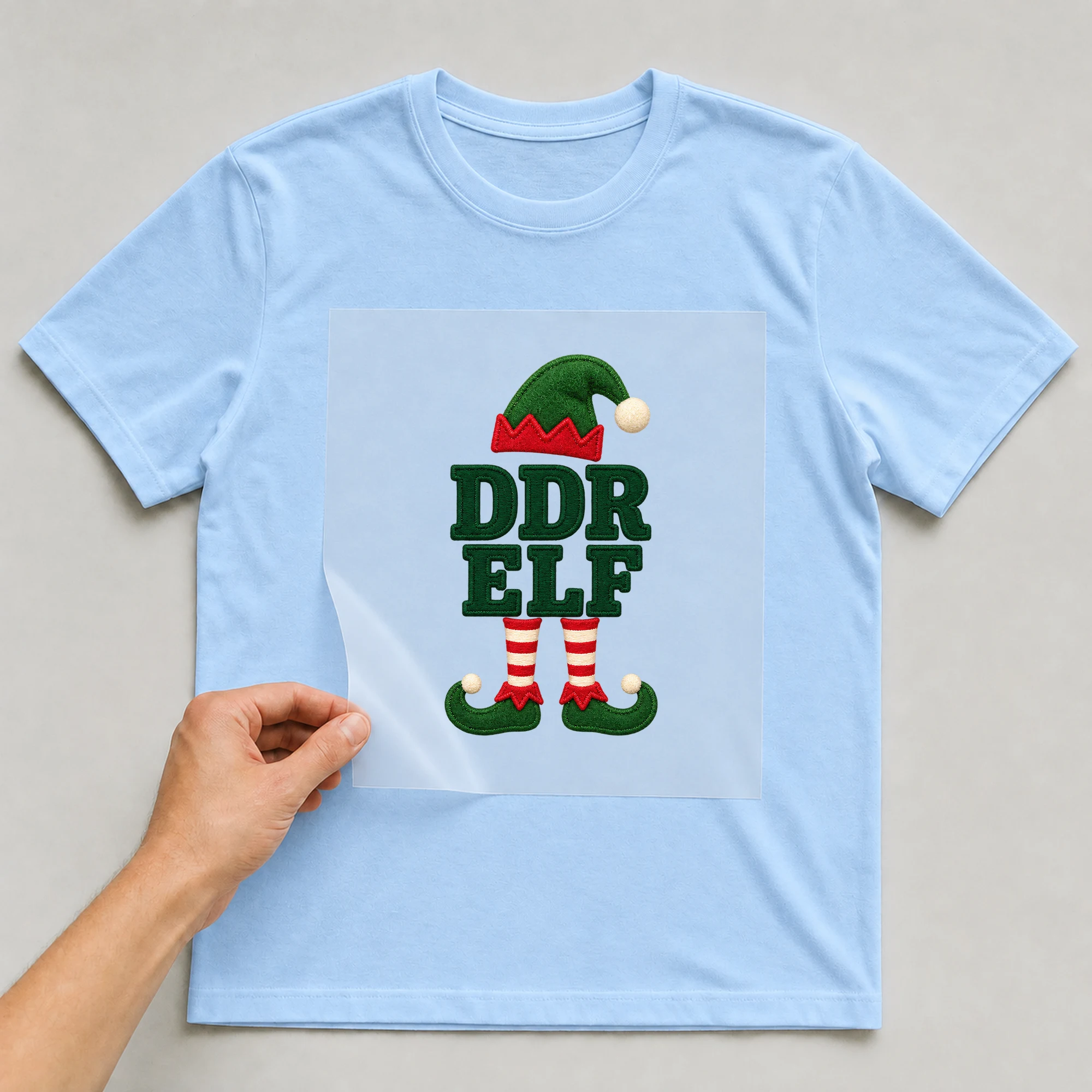 Bügelbild „Ddr Elf“ auf babyblauem T-Shirt, Folie wird aufgelegt