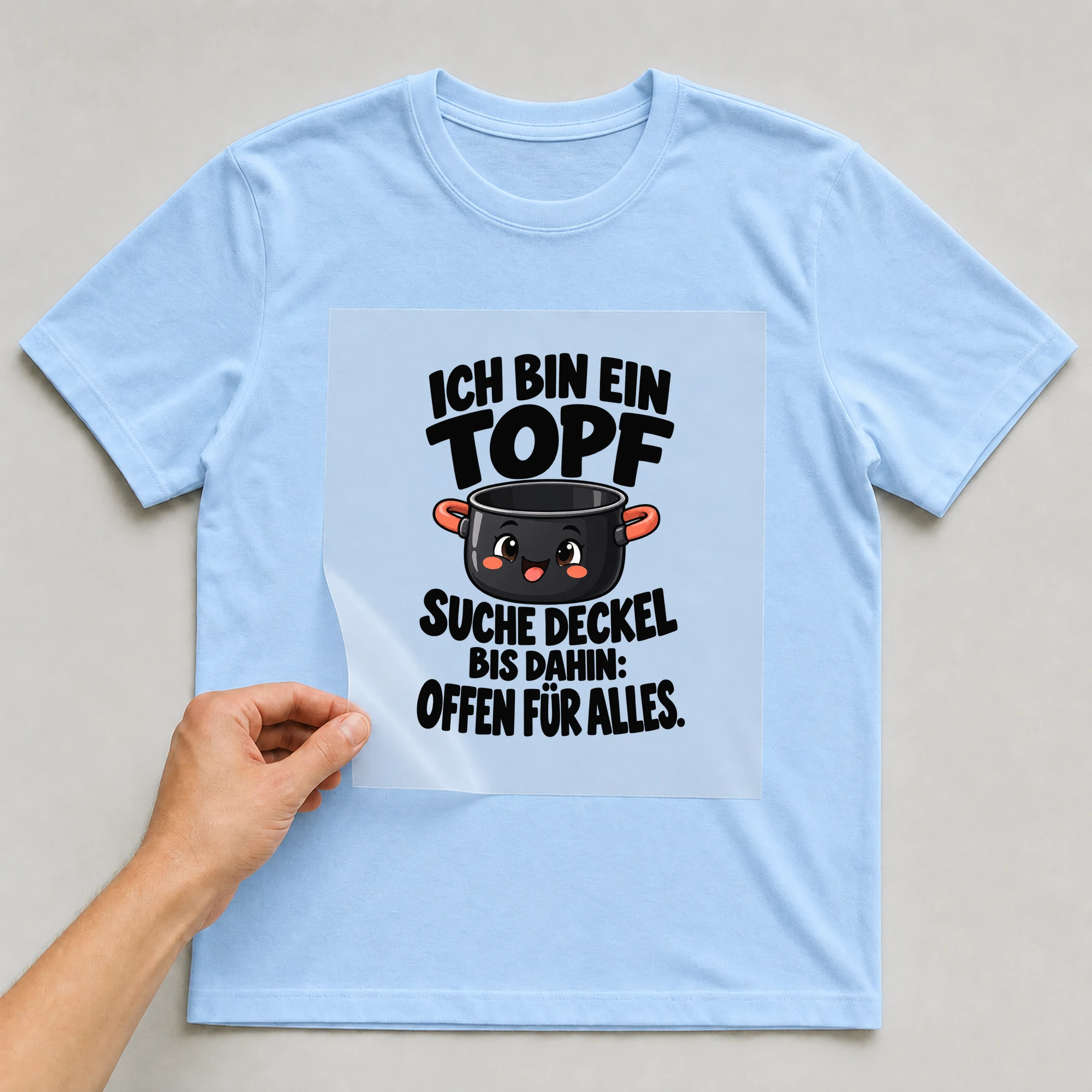 Bügelbild „Ich Bin Ein Topf Suche Deckel Bis Dahin: Offen Für Alles.“ auf babyblauem T-Shirt, Folie wird aufgelegt