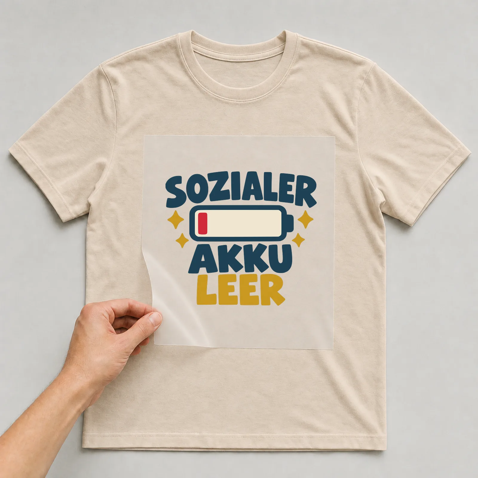 Bügelbild Sozialer Akku leer auf beigem T-Shirt, Folie wird aufgelegt