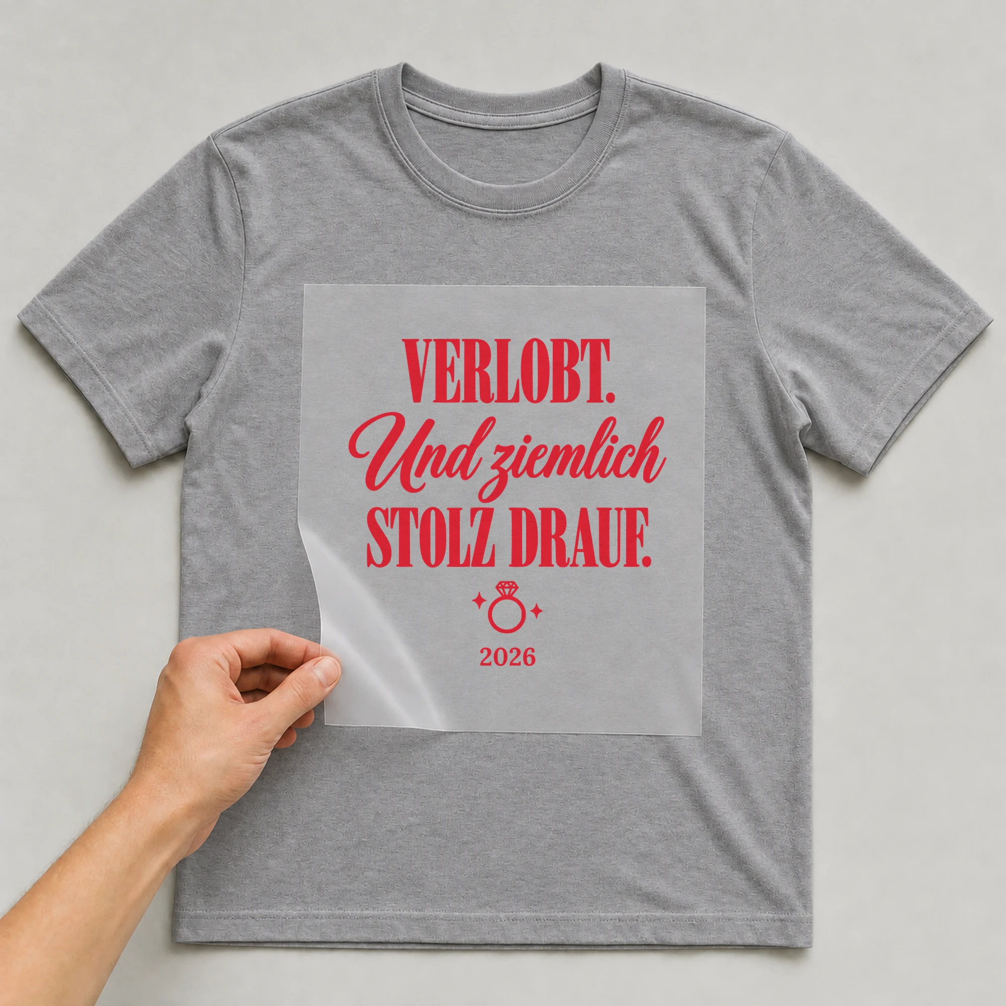 Bügelbild Verlobt. Und ziemlich stolz drauf mit Jahr auf grauem T-Shirt, Folie wird aufgelegt