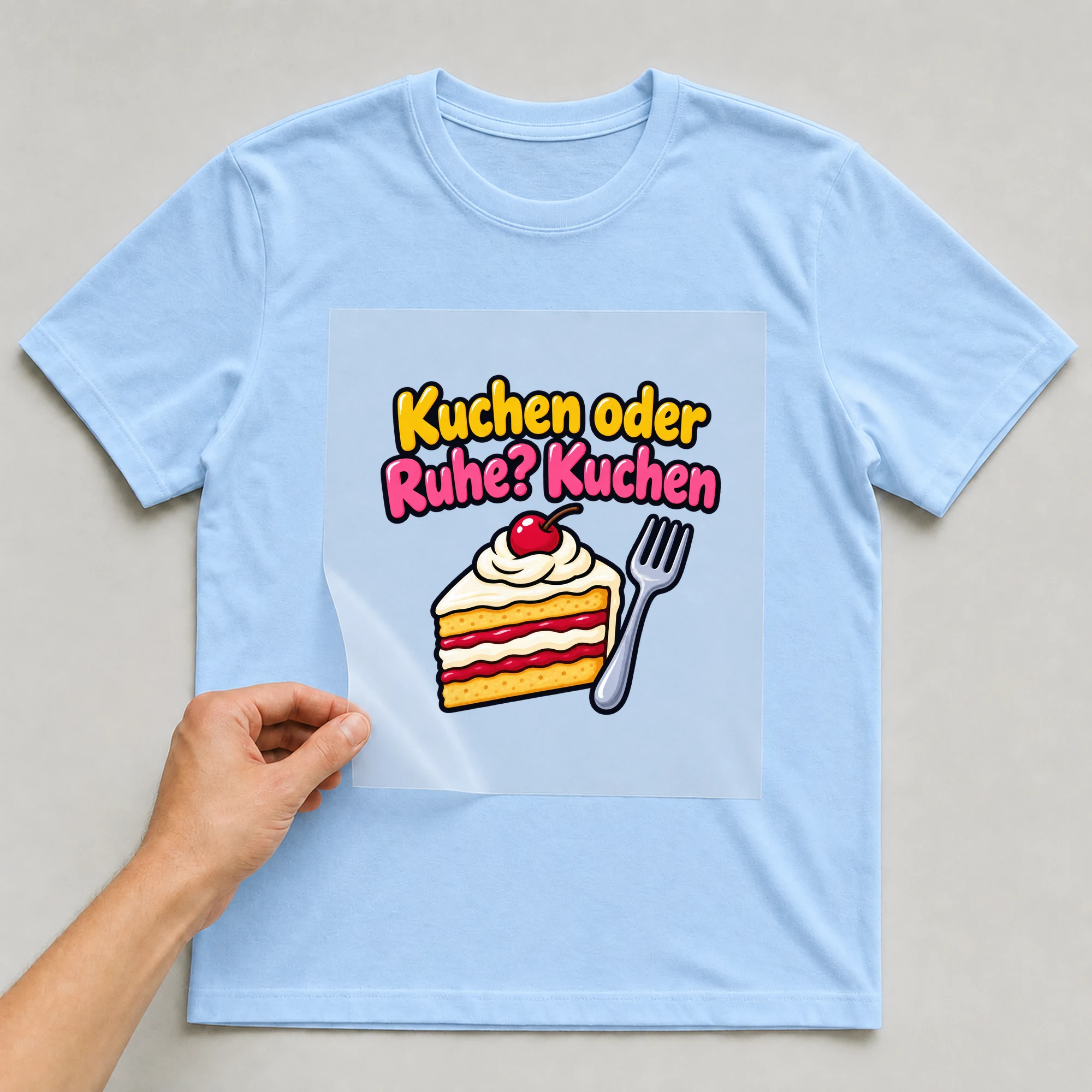 Bügelbild „Kuchen oder Ruhe? Kuchen“ auf babyblauem T-Shirt, Folie wird aufgelegt