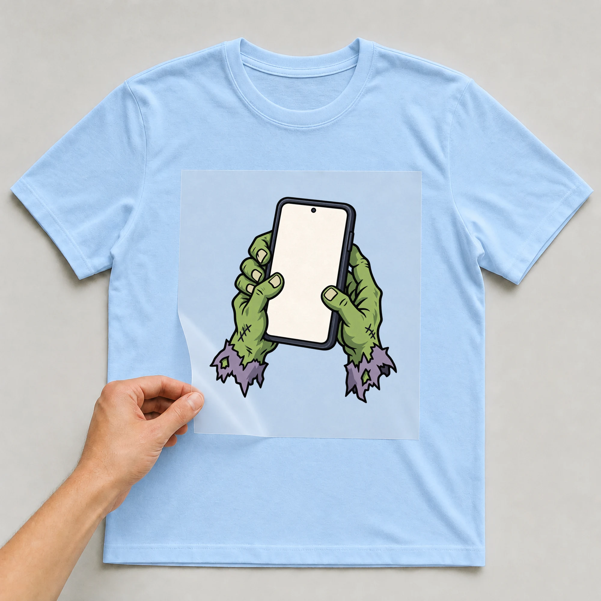 Bügelbild „Zombie Phone“ auf babyblauem T-Shirt, Folie wird aufgelegt
