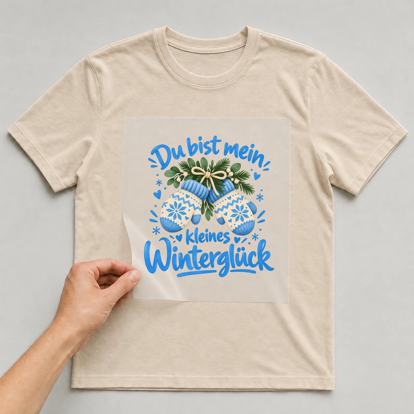 Bügelbild „Du bist mein kleines Winterglück“ auf beigem T-Shirt, Folie wird aufgelegt