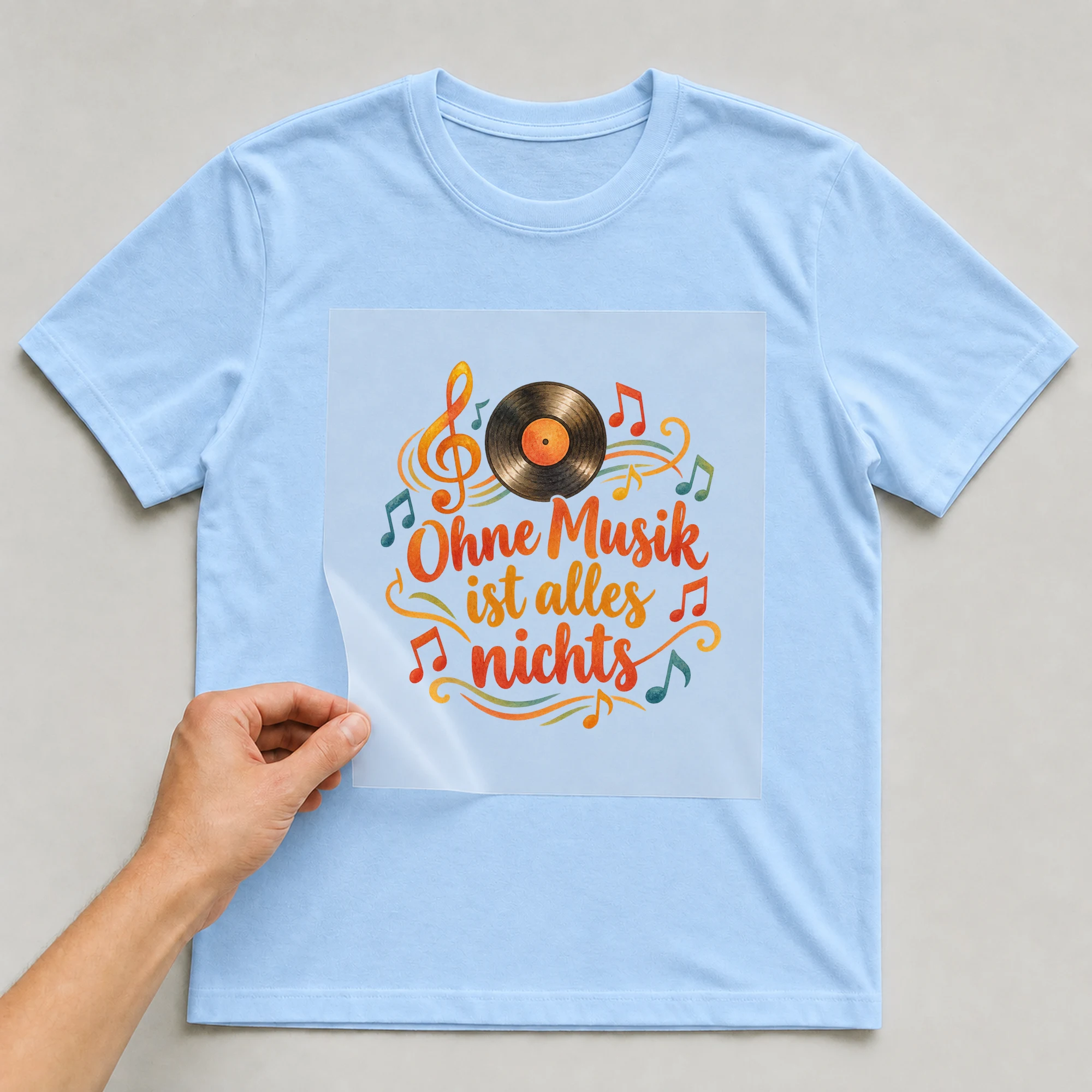 Bügelbild „Ohne Musik ist alles nichts“ auf babyblauem T-Shirt, Folie wird aufgelegt