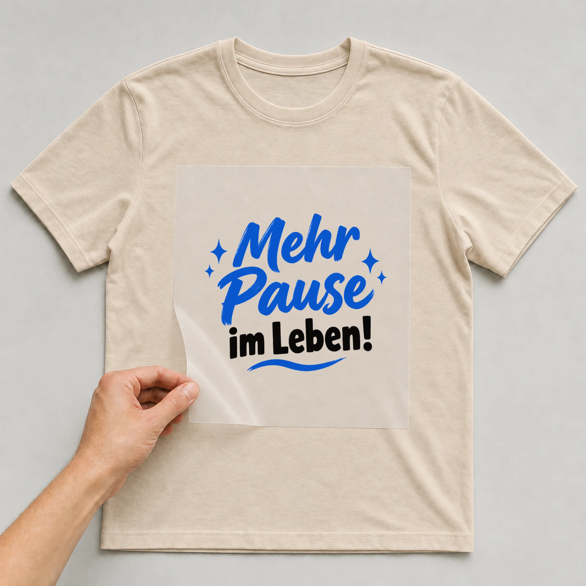 Bügelbild „Mehr Pause im Leben!“ auf beigem T-Shirt, Folie wird aufgelegt