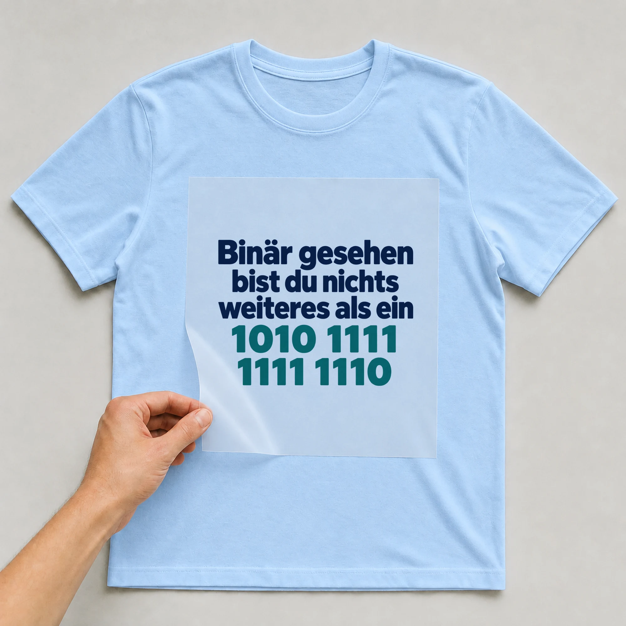 Bügelbild „Binär gesehen bist du nichts weiteres als ein 1010 1111 1111 1110“ auf babyblauem T-Shirt, Folie wird aufgelegt