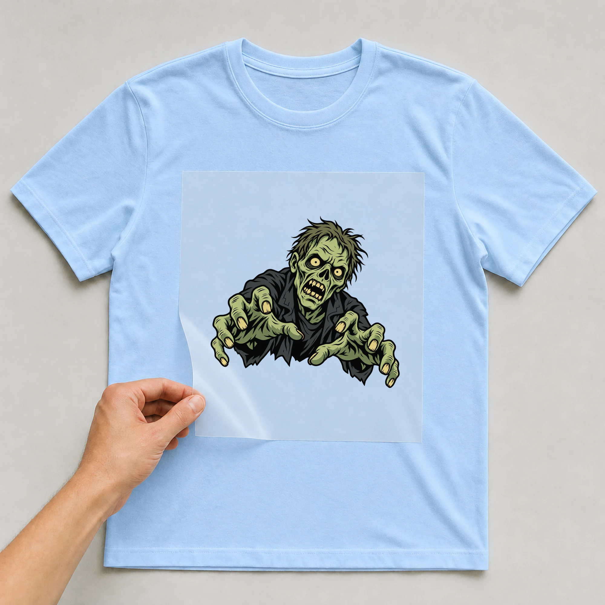 Bügelbild „Zombie Fleisch“ auf babyblauem T-Shirt, Folie wird aufgelegt