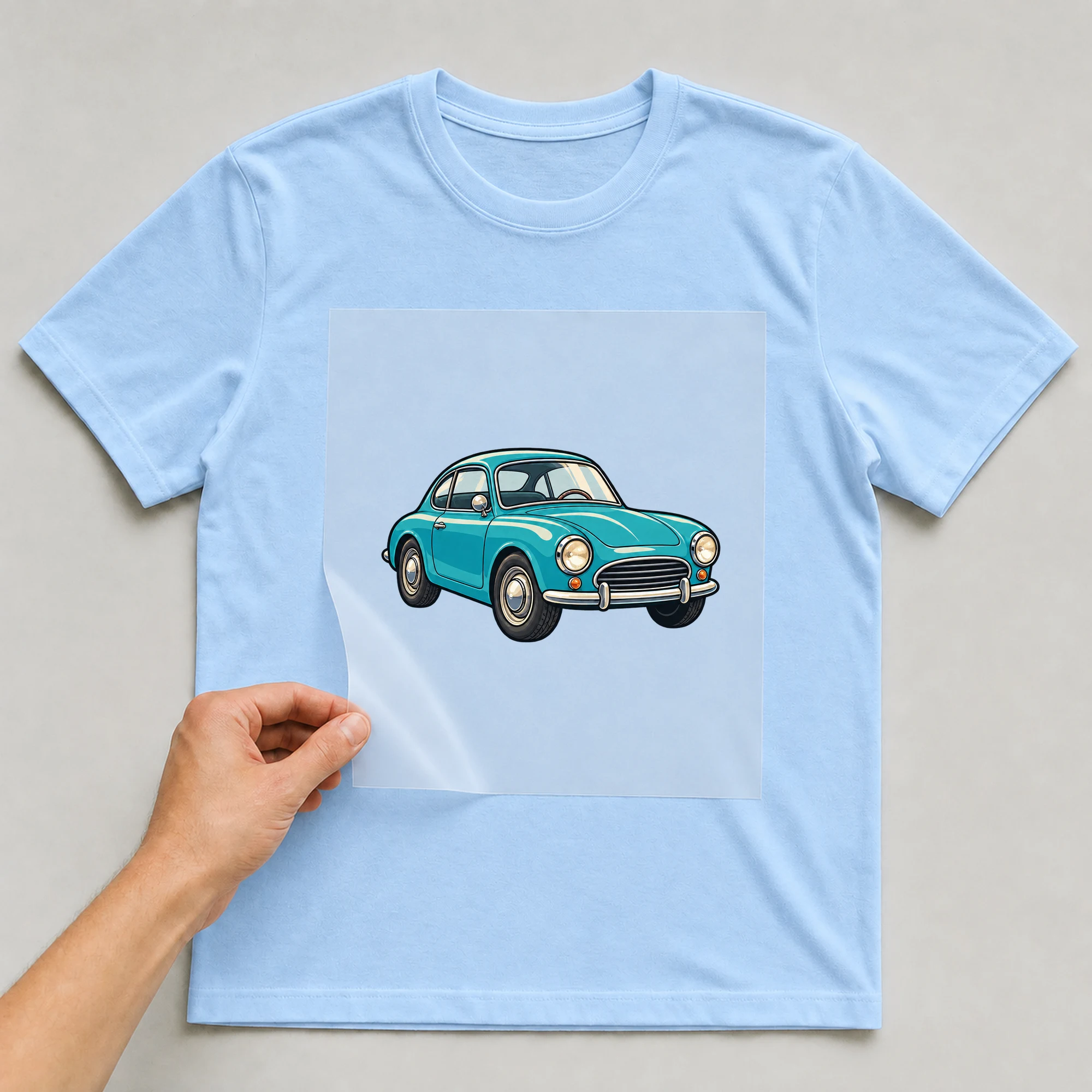 Bügelbild „Türkises Retro-Auto“ auf babyblauem T-Shirt, Folie wird aufgelegt