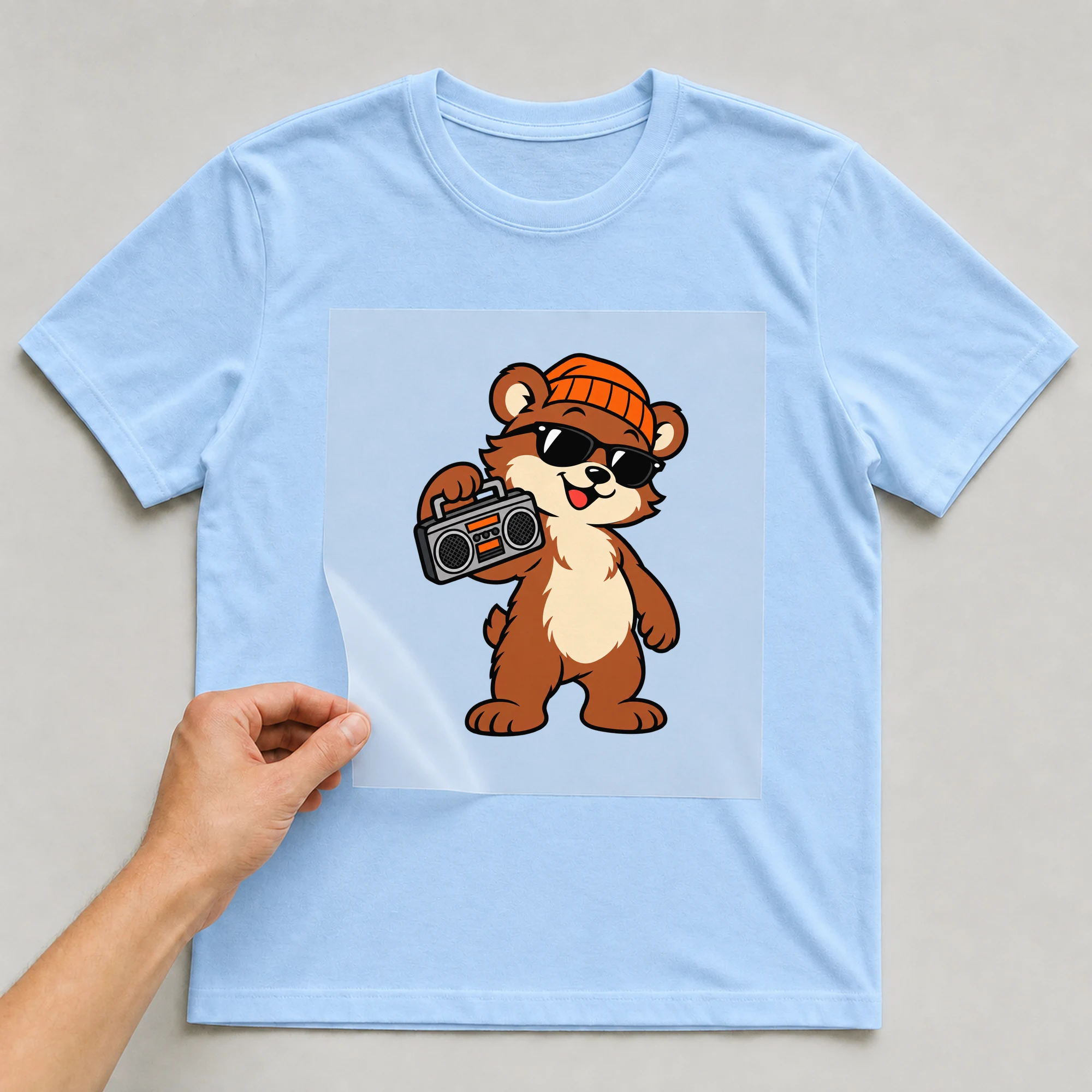 Bügelbild „Cool Bear“ auf babyblauem T-Shirt, Folie wird aufgelegt