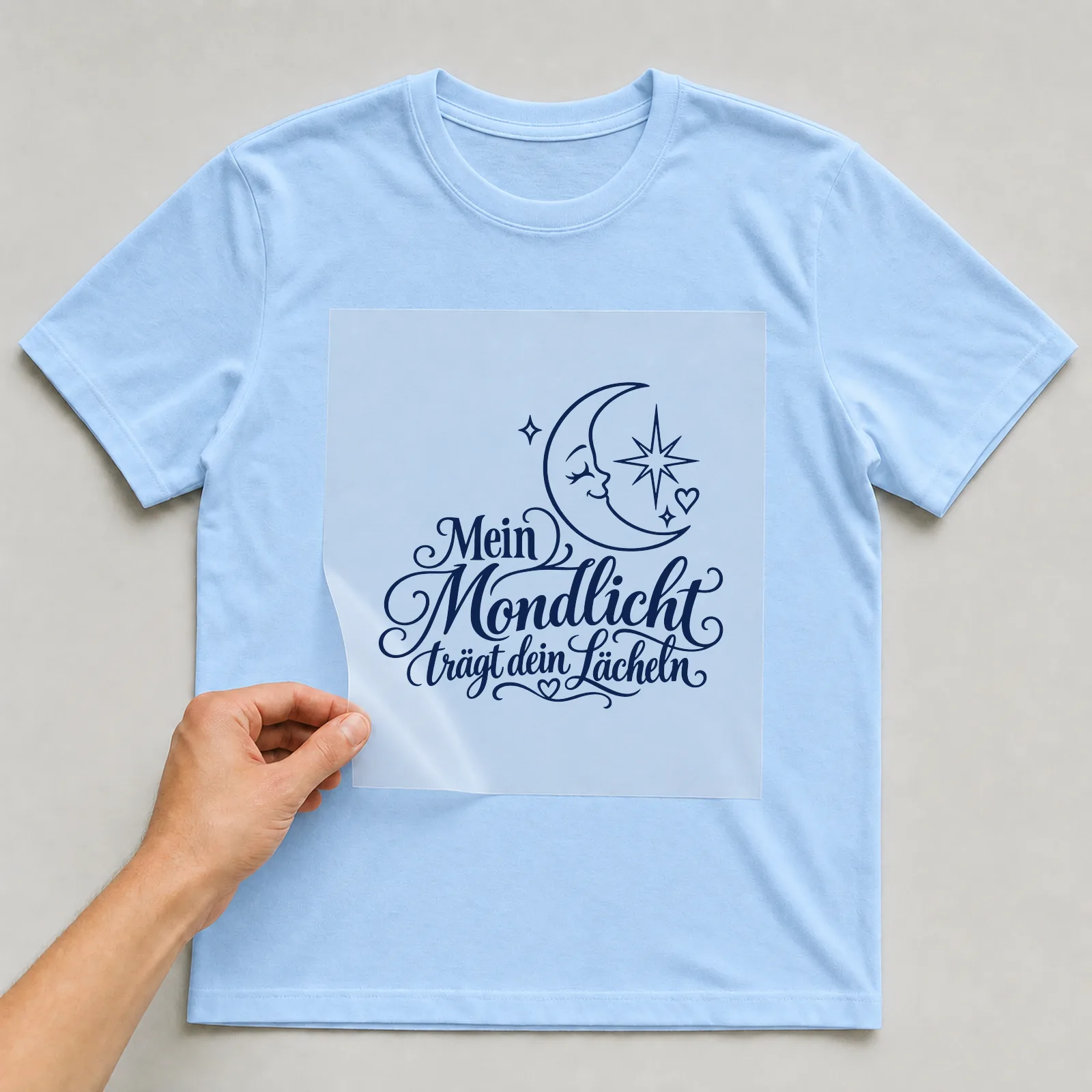 Bügelbild „Mein Mondlicht trägt dein Lächeln“ auf hellblauem T-Shirt, Folie wird aufgelegt