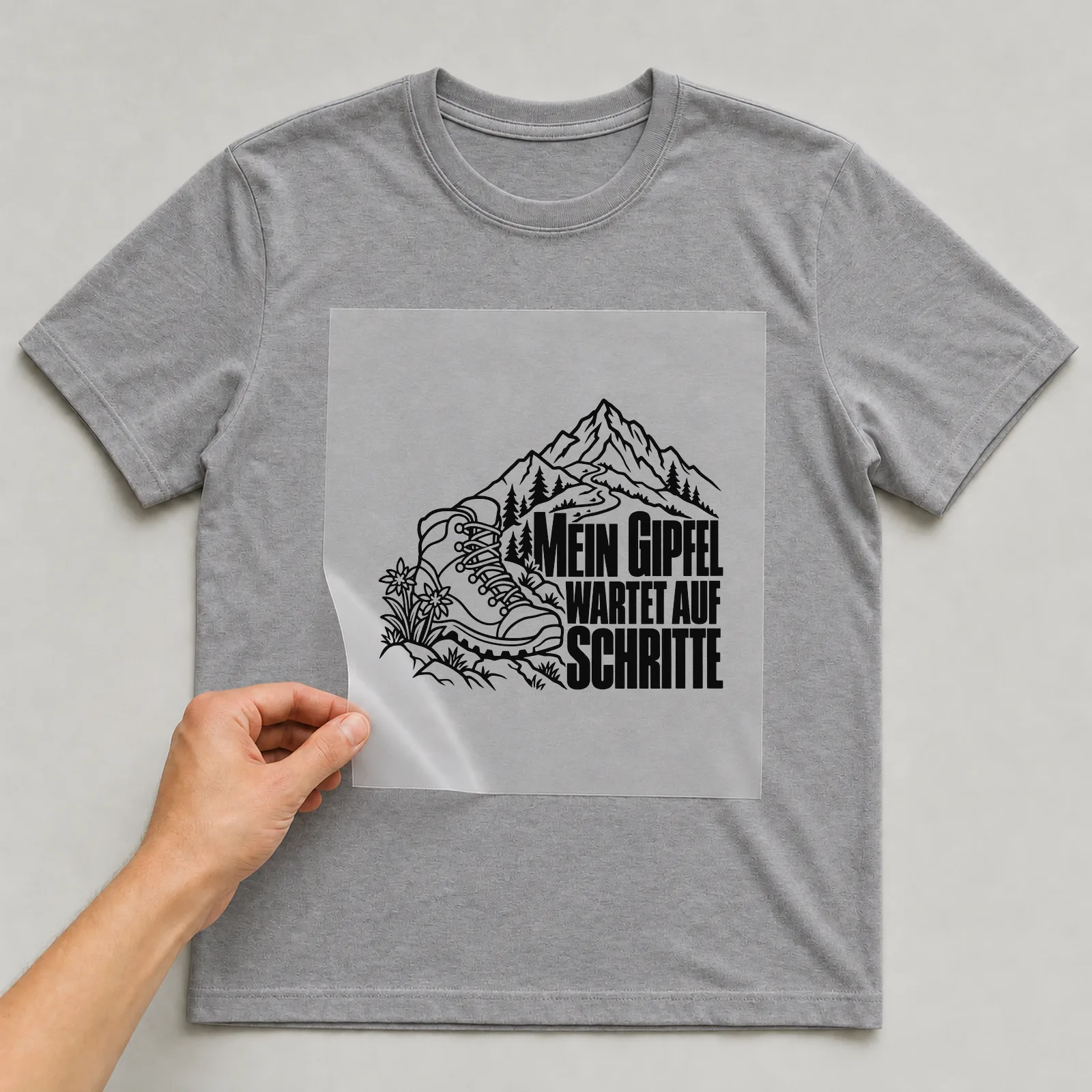 Bügelbild „Mein Gipfel wartet auf Schritte“ auf grauem T-Shirt, Folie wird aufgelegt