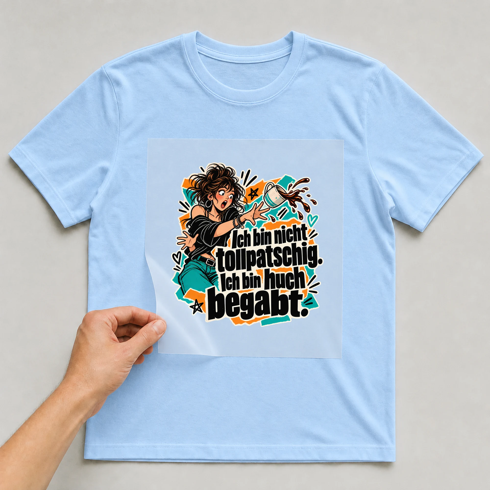 Bügelbild „Ich bin nicht tollpatschig. Ich bin hoch begabt.“ auf babyblauem T-Shirt, Folie wird aufgelegt
