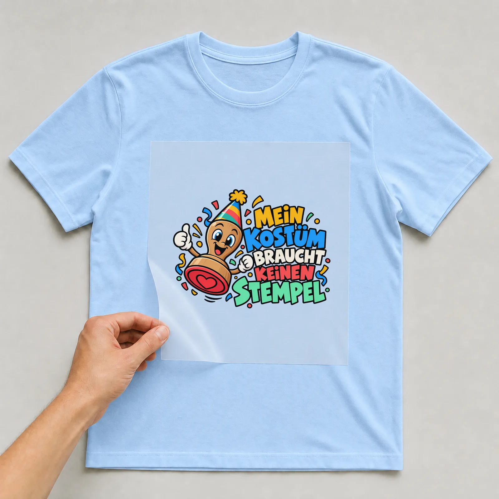 Bügelbild „Mein Kostüm braucht keinen Stempel“ auf hellblauem T-Shirt, Folie wird aufgelegt