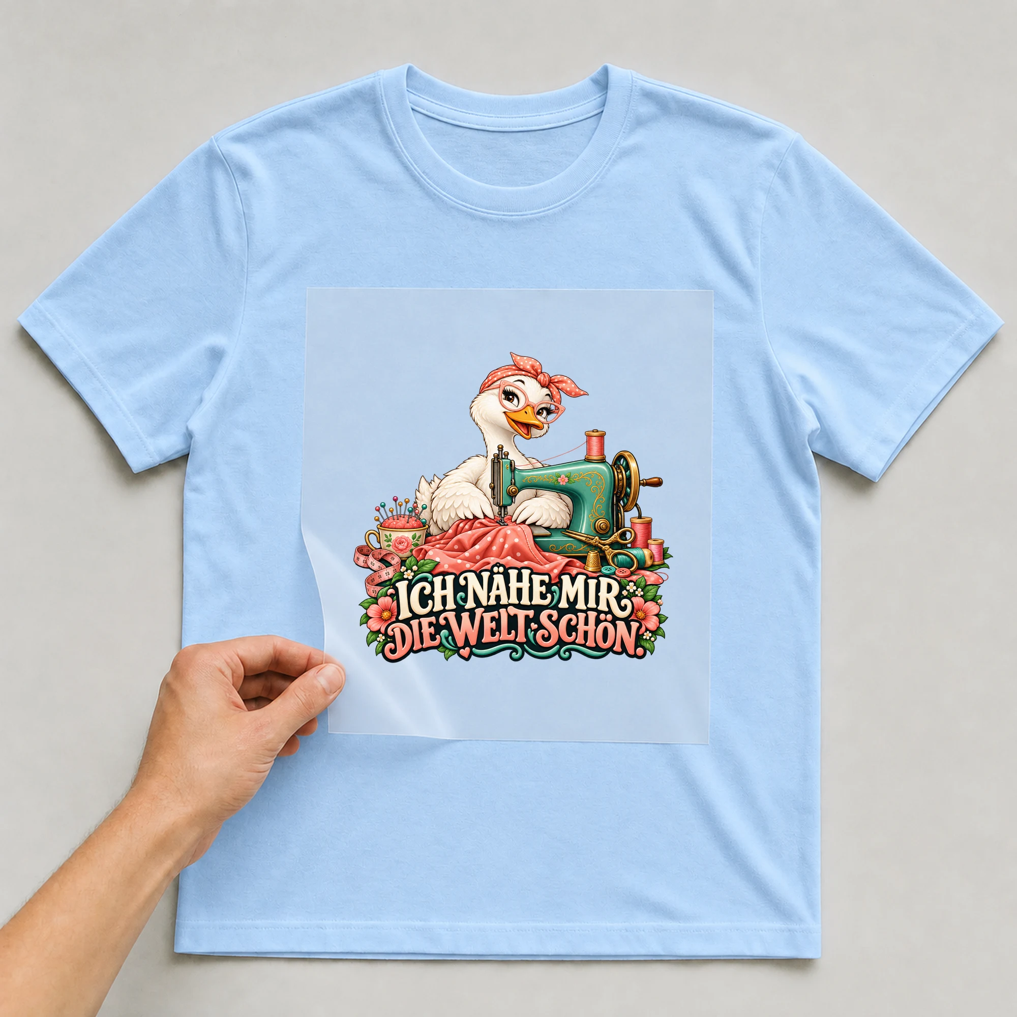 Bügelbild „Ich nähe mir die Welt schön.“ auf babyblauem T-Shirt, Folie wird aufgelegt