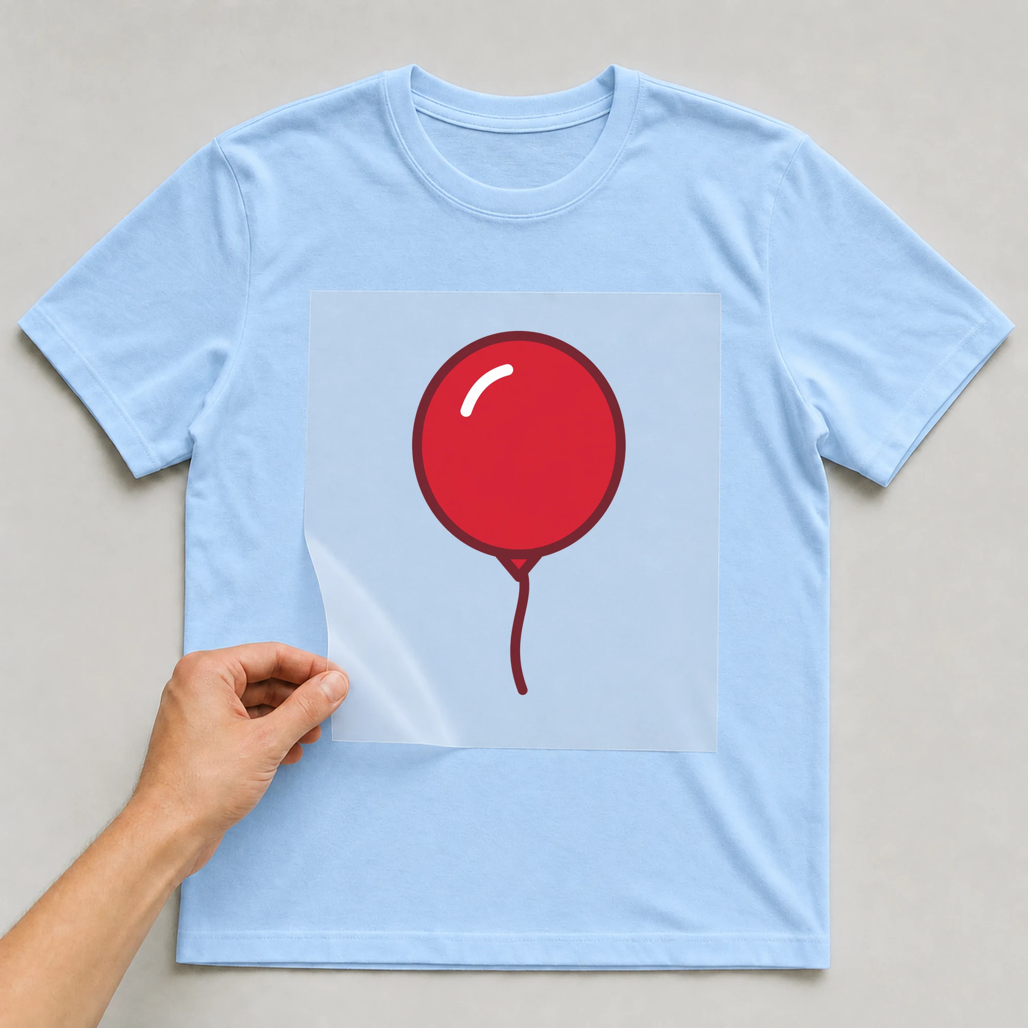 Bügelbild „Luftballon“ auf babyblauem T-Shirt, Folie wird aufgelegt