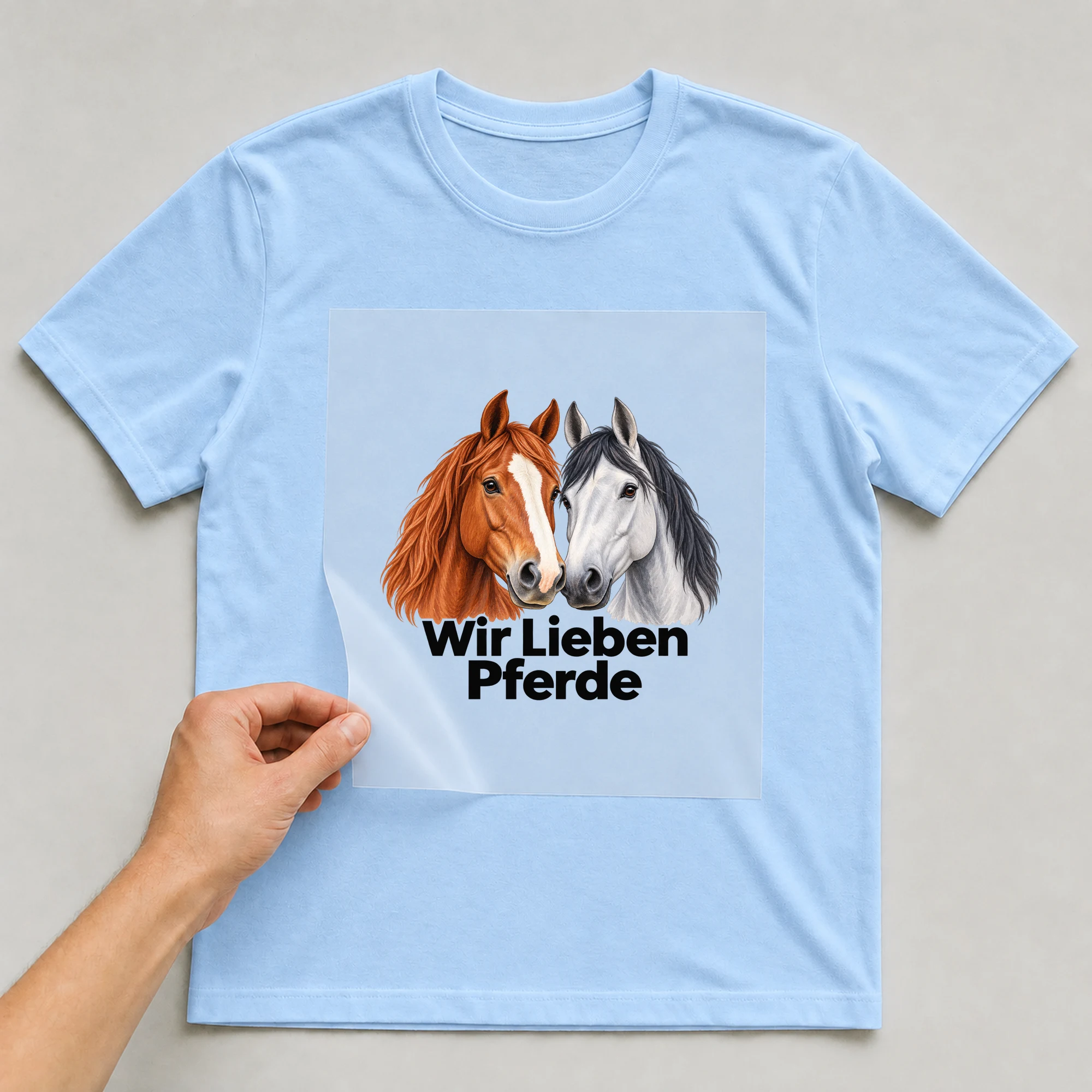 Bügelbild „Wir Lieben Pferde“ auf babyblauem T-Shirt, Folie wird aufgelegt