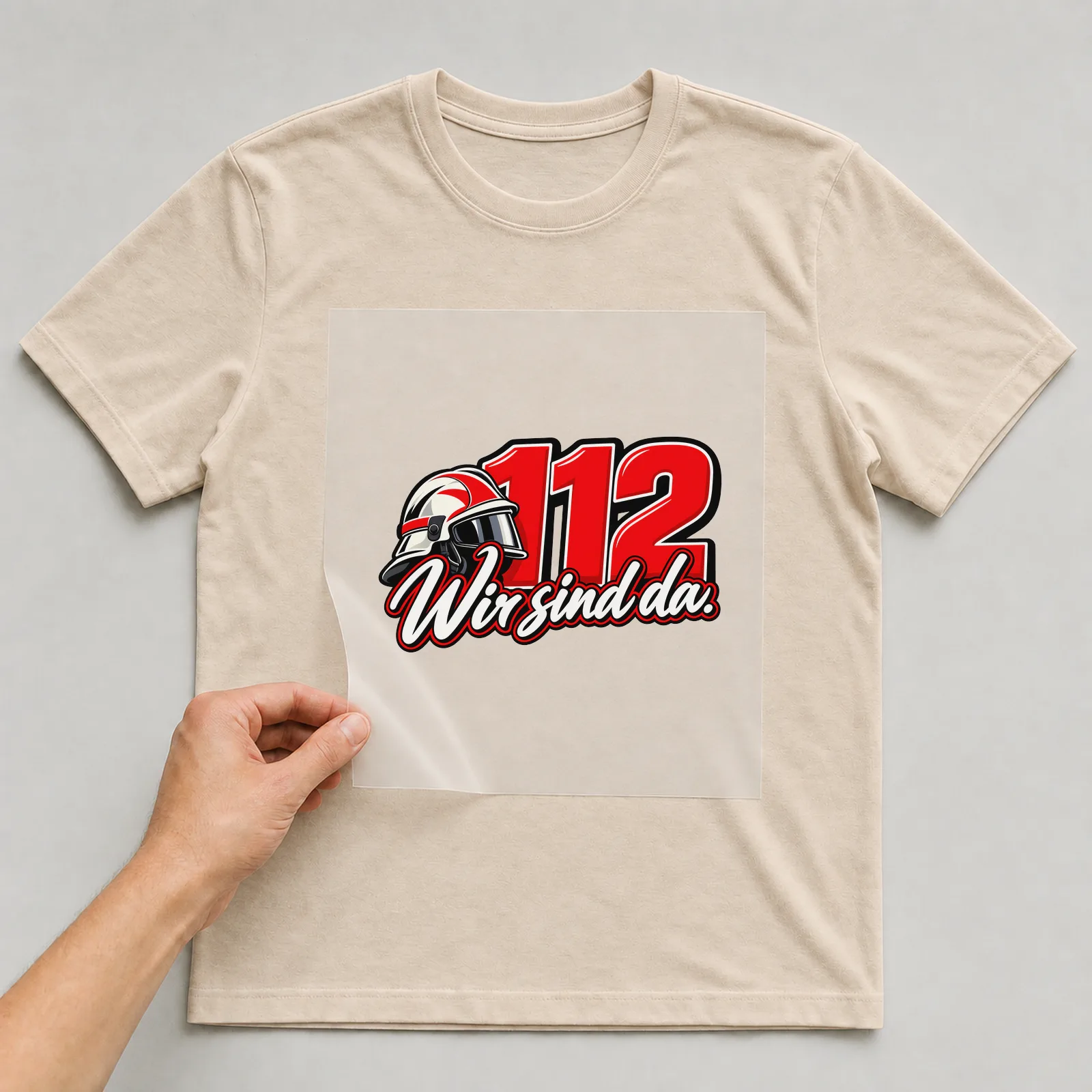 Bügelbild „112 Wir sind da“ auf beigem T-Shirt, Folie wird aufgelegt