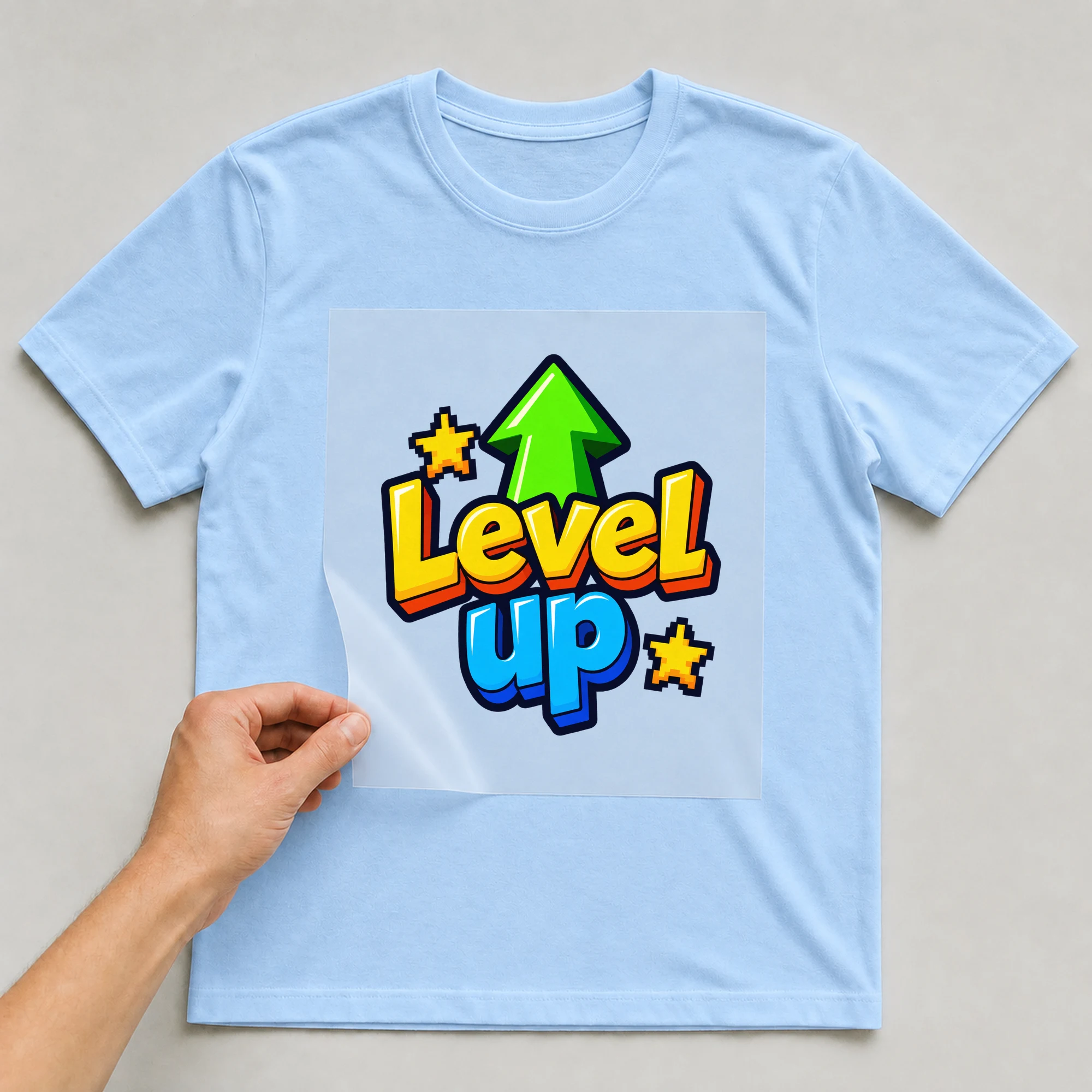Bügelbild „Level up“ auf babyblauem T-Shirt, Folie wird aufgelegt