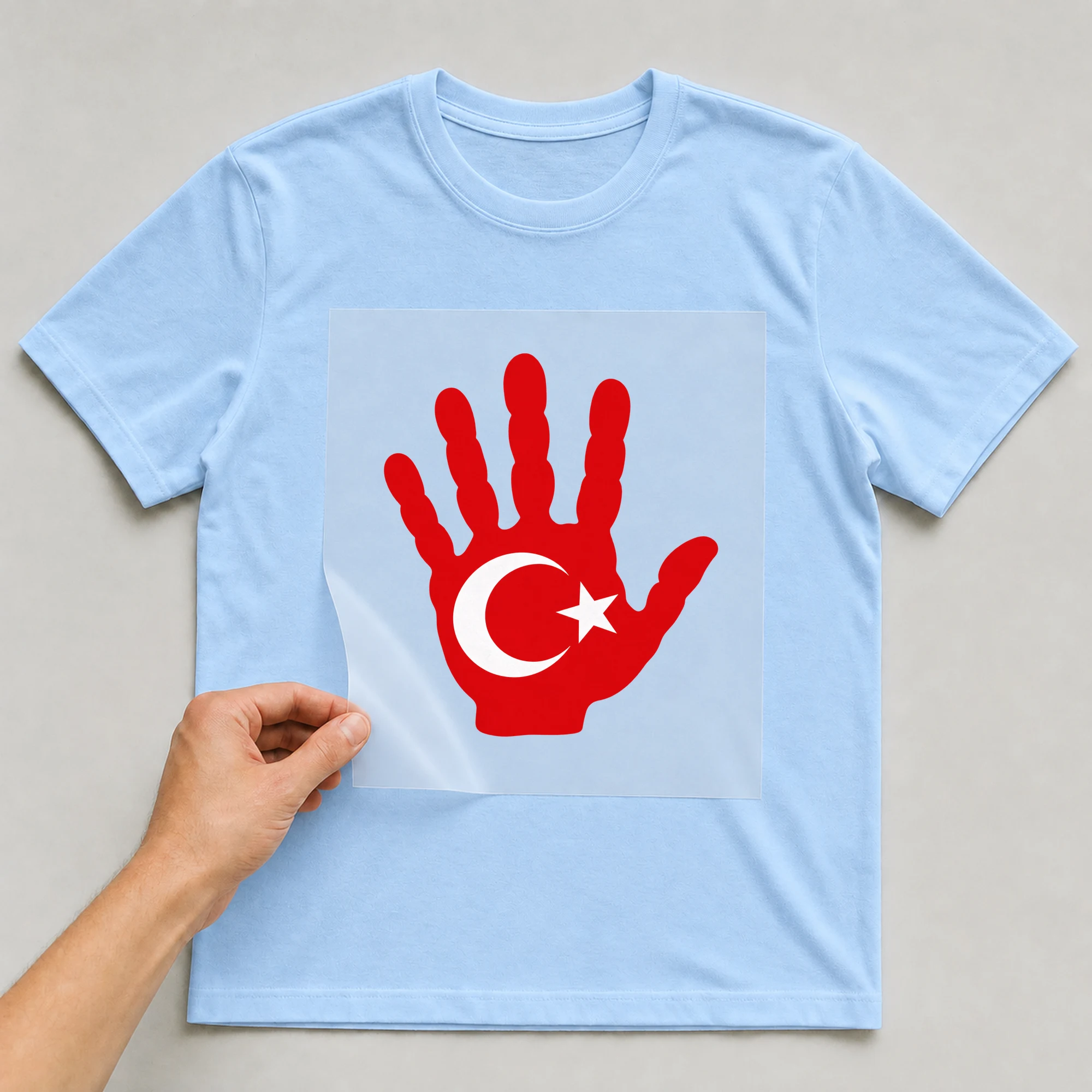 Bügelbild „Hand Türkei“ auf babyblauem T-Shirt, Folie wird aufgelegt