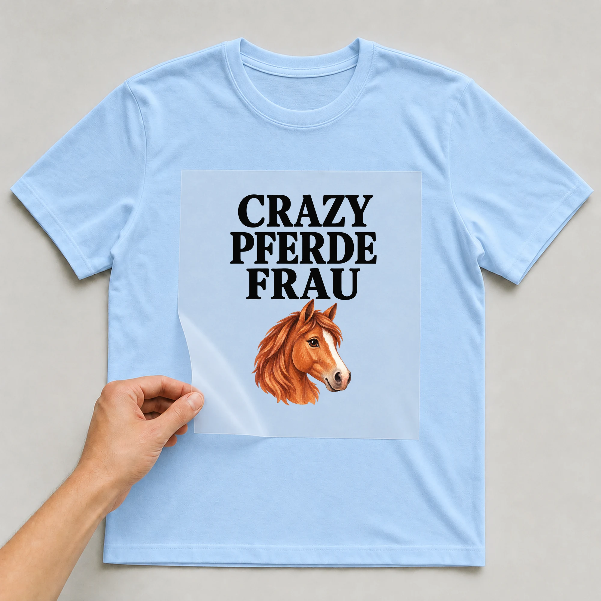 Bügelbild „Crazy Pferde Frau“ auf babyblauem T-Shirt, Folie wird aufgelegt