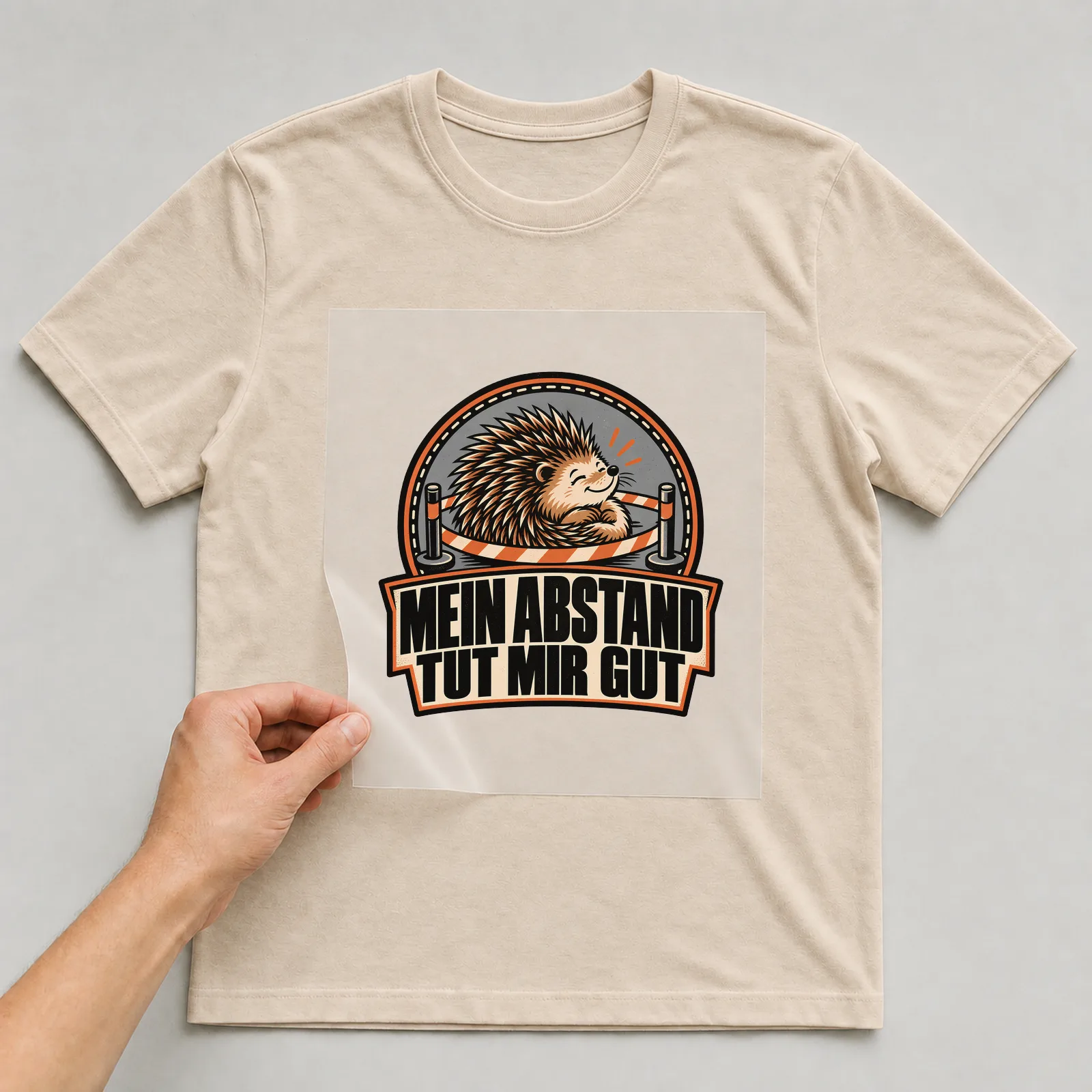 Bügelbild „Mein Abstand tut mir gut“ auf beigem T-Shirt, Folie wird aufgelegt
