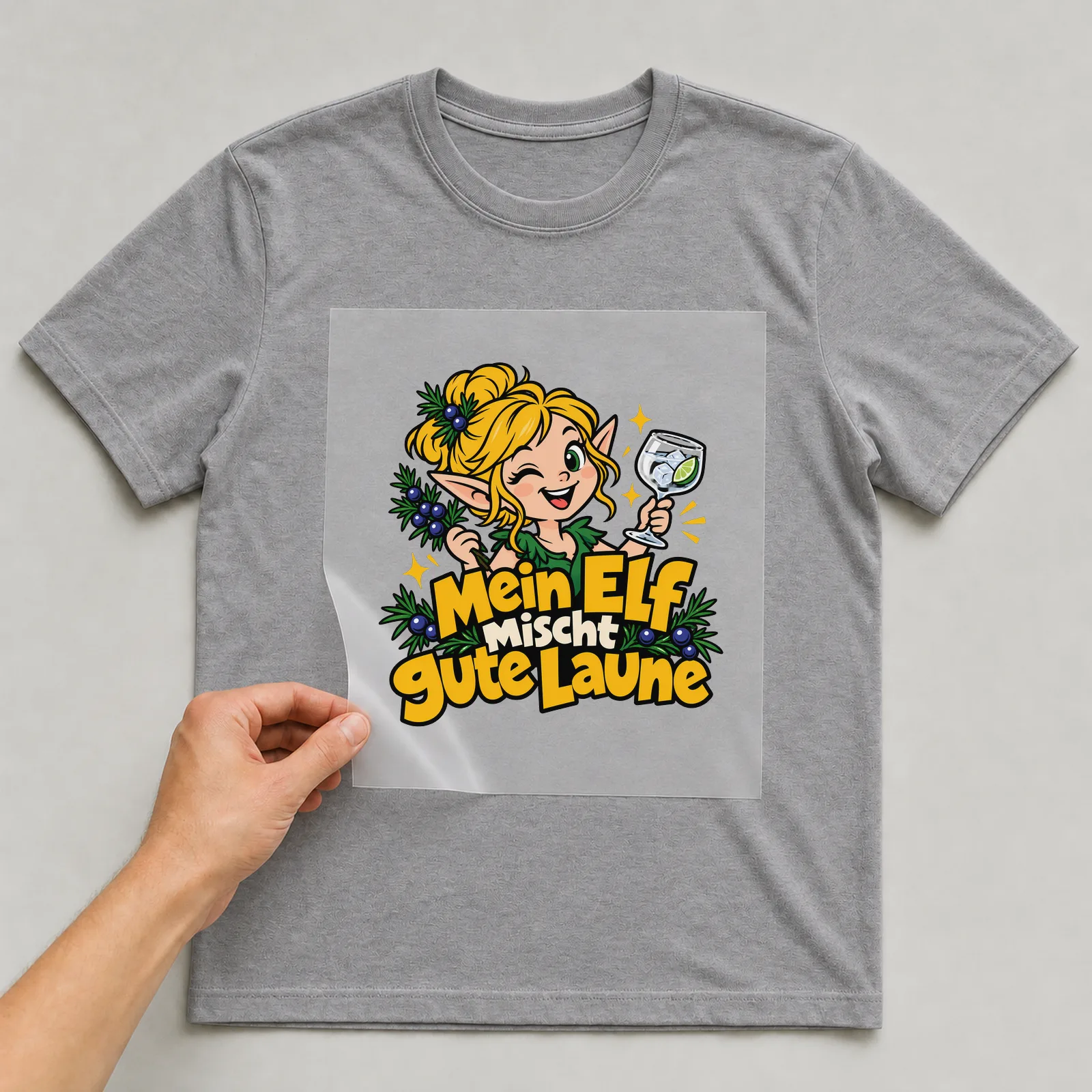 Bügelbild „Mein Elf mischt gute Laune“ auf grauem T-Shirt, Folie wird aufgelegt