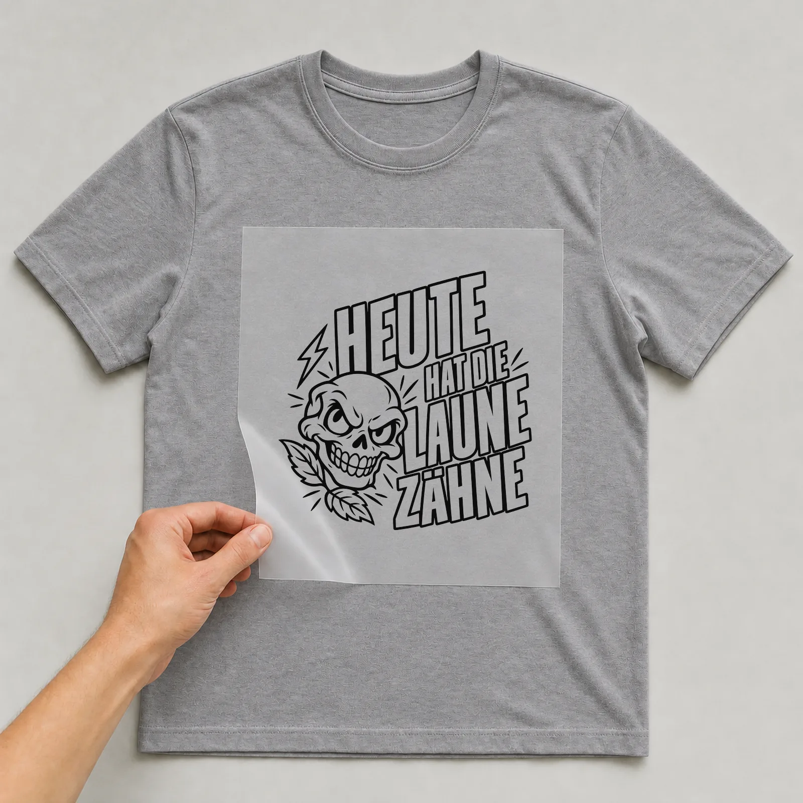 Bügelbild „Heute hat die Laune zähne“ auf grauem T-Shirt, Folie wird aufgelegt