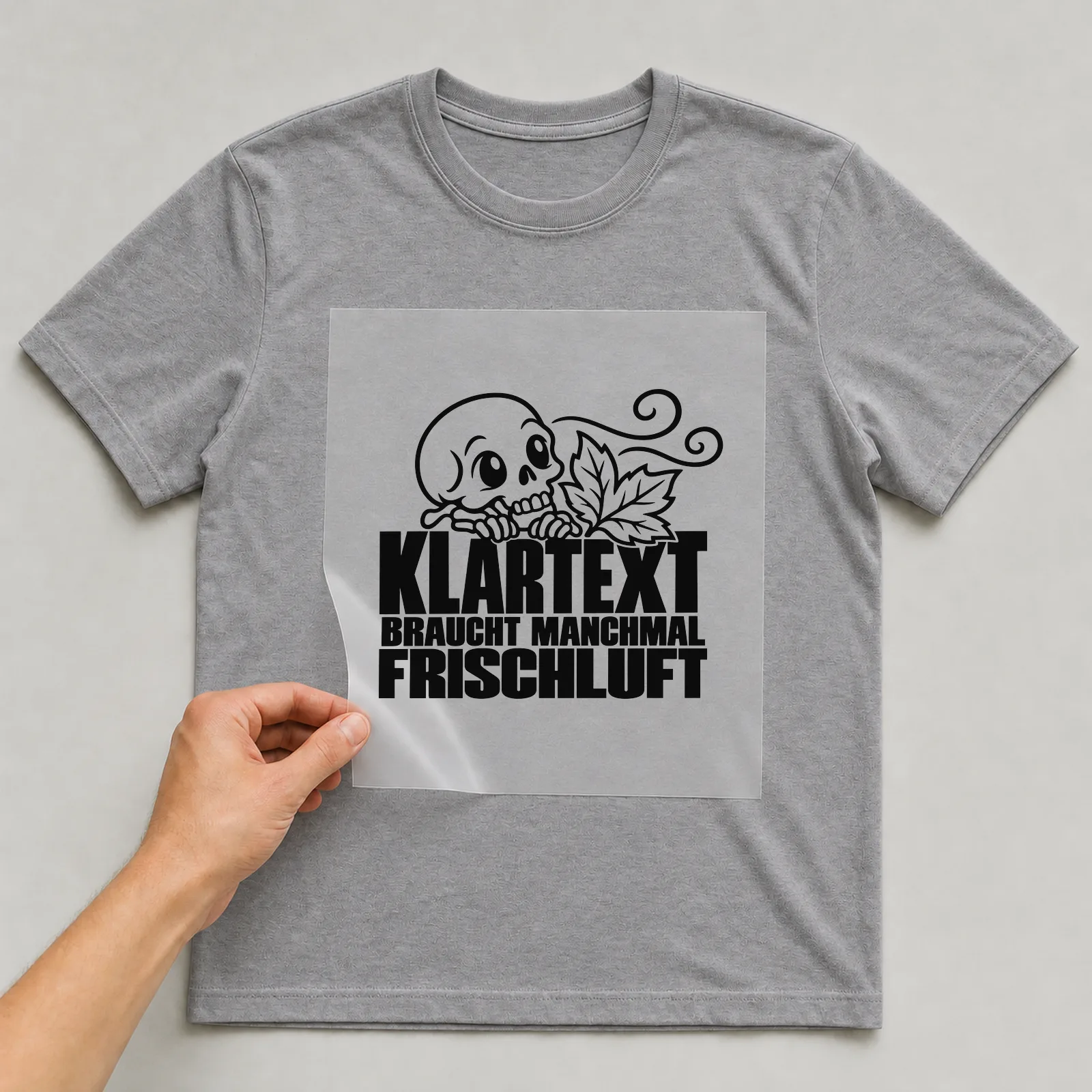 Bügelbild „Klartext braucht manchmal Frischluft“ auf grauem T-Shirt, Folie wird aufgelegt
