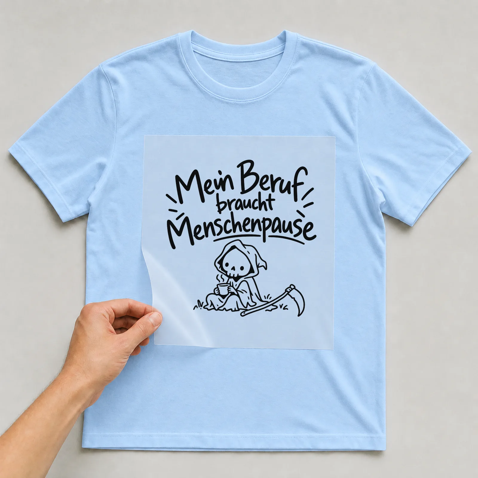 Bügelbild „Mein Beruf braucht Menschenpause“ auf hellblauem T-Shirt, Folie wird aufgelegt