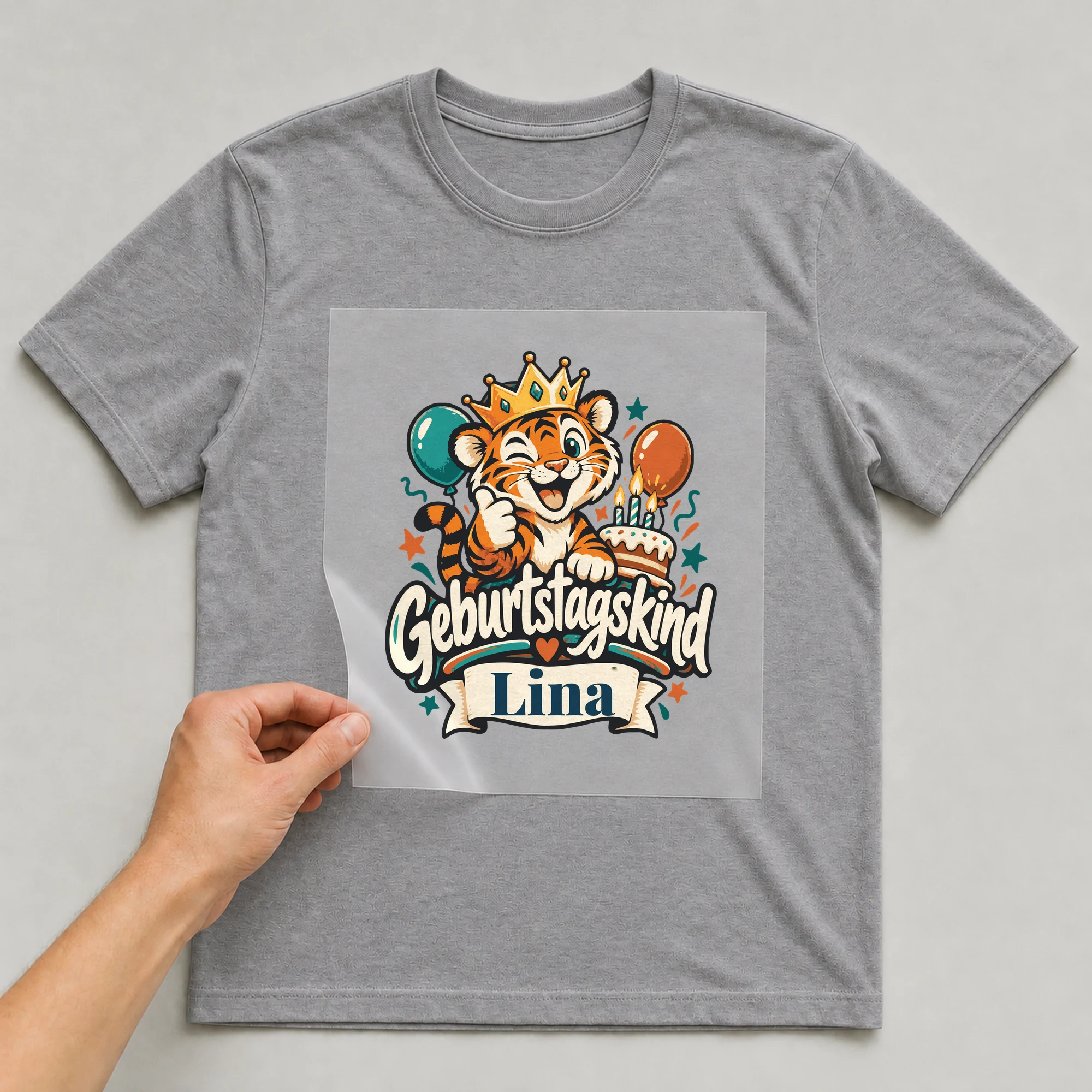 Bügelbild Geburtstagskind mit Name auf grauem T-Shirt, Folie wird aufgelegt