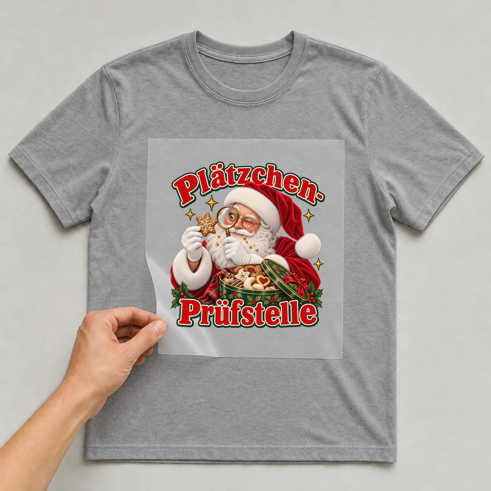 Bügelbild Plätzchen-Prüfstelle (Freche Weihnachtsklassiker) auf grauem T-Shirt, Folie wird aufgelegt