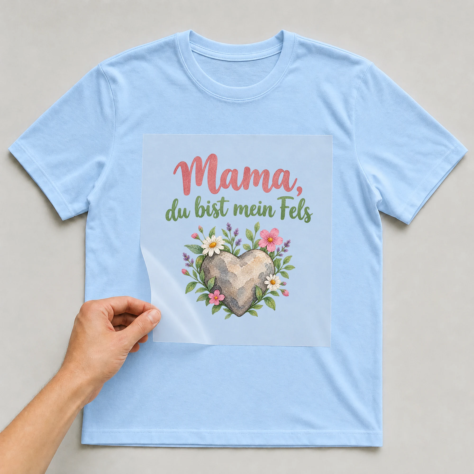Bügelbild „Mama, du bist mein Fels“ auf babyblauem T-Shirt, Folie wird aufgelegt