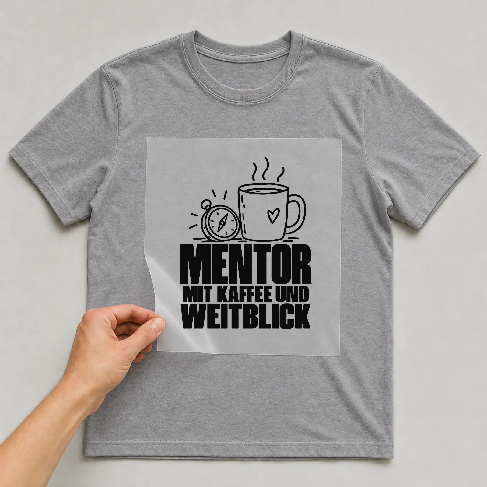 Bügelbild „Mentor mit Kaffee und Weitblick“ auf grauem T-Shirt, Folie wird aufgelegt