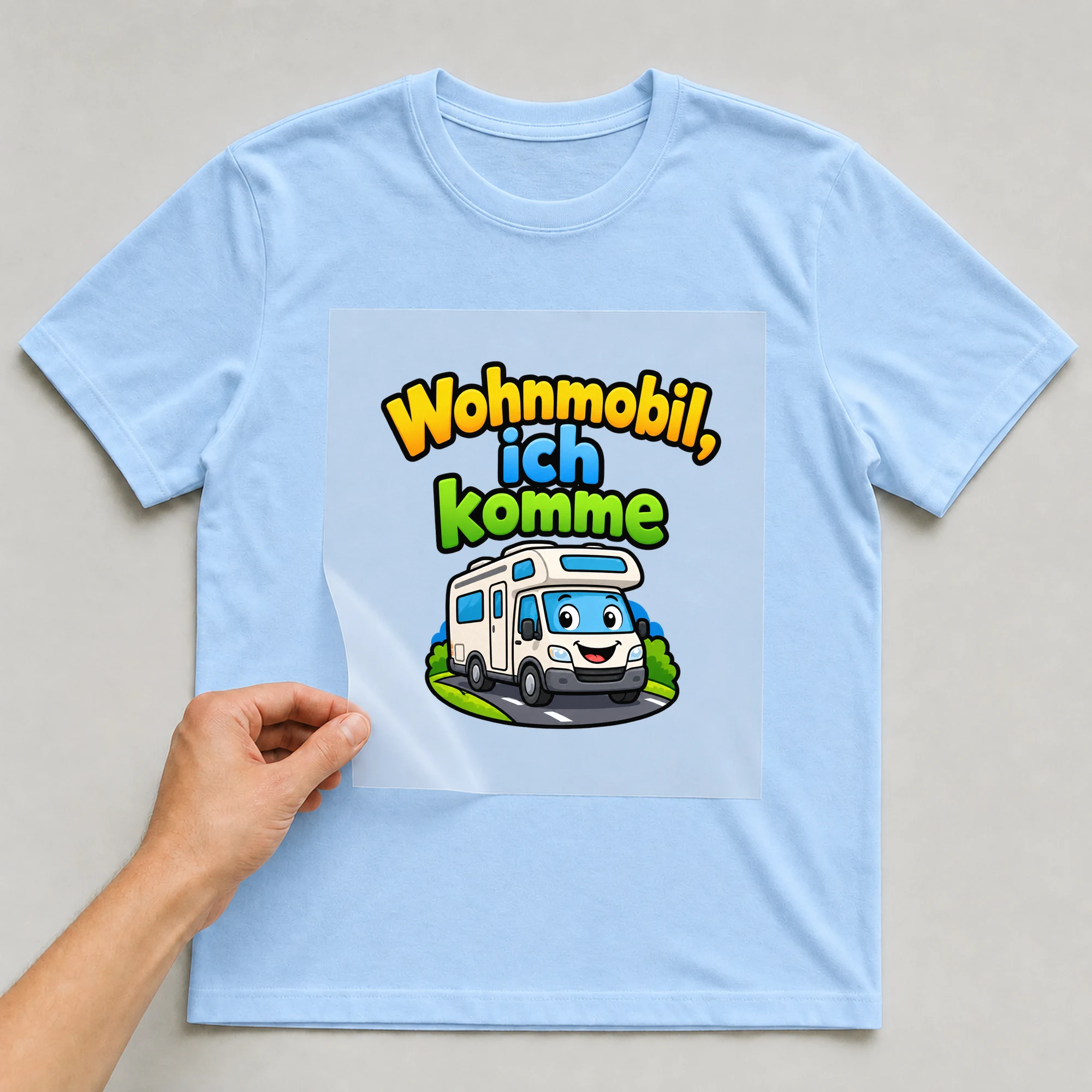 Bügelbild „Wohnmobil ich komme“ auf babyblauem T-Shirt, Folie wird aufgelegt
