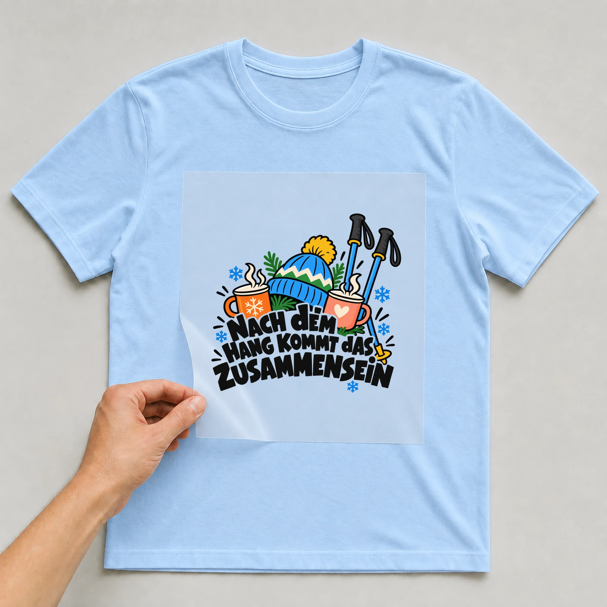 Bügelbild „Nach dem Hang kommt das Zusammensein“ auf babyblauem T-Shirt, Folie wird aufgelegt