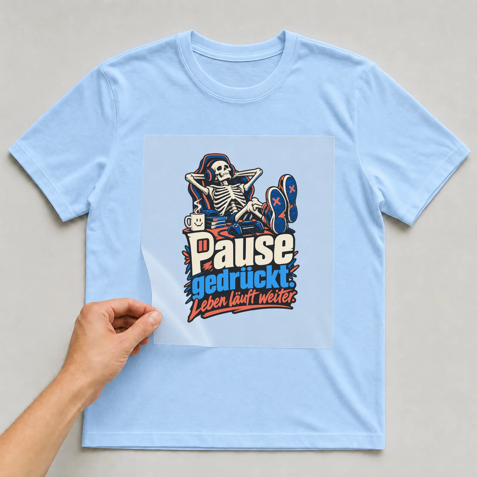 Bügelbild Pause gedrückt. Leben läuft weiter. auf hellblauem T-Shirt, Folie wird aufgelegt