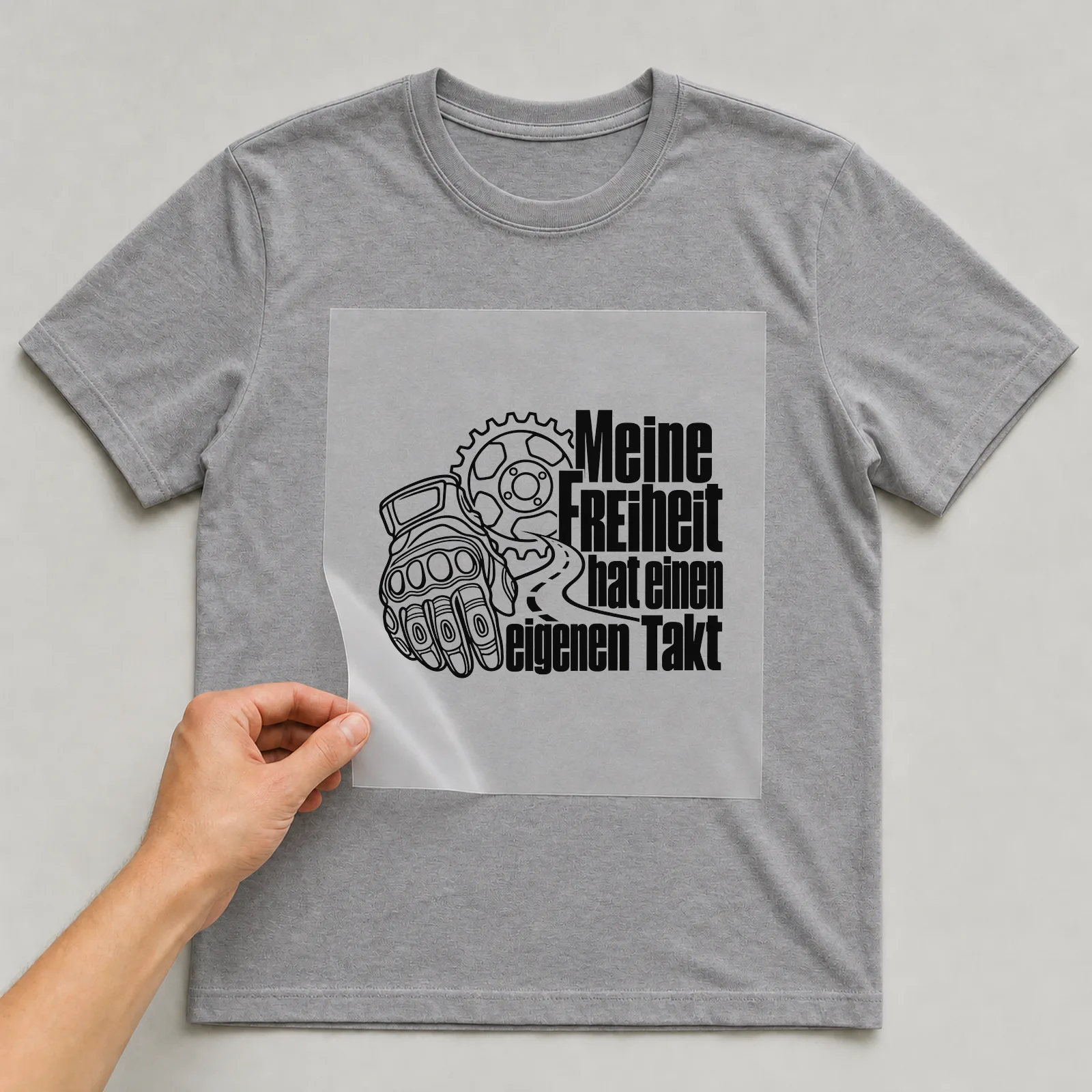 Bügelbild „Meine FREIHEIT hat einen eigenen Takt“ auf grauem T-Shirt, Folie wird aufgelegt