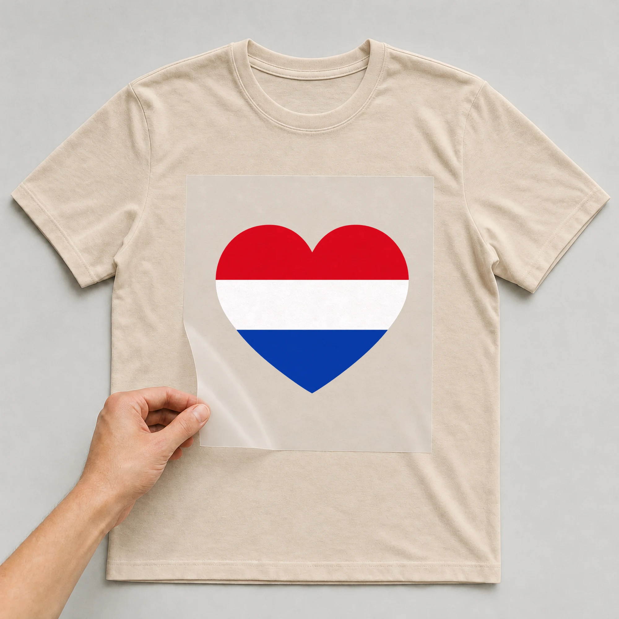 Bügelbild „Herz Flagge Niederlande“ auf beigem T-Shirt, Folie wird aufgelegt