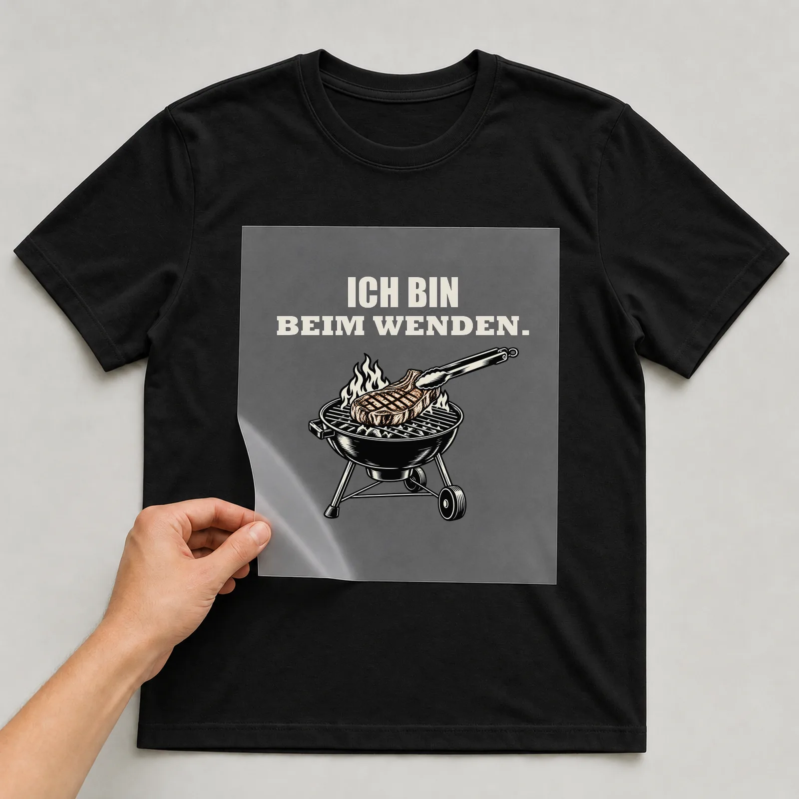 Bügelbild „Ich bin beim Wenden“ auf schwarzem T-Shirt, Folie wird aufgelegt