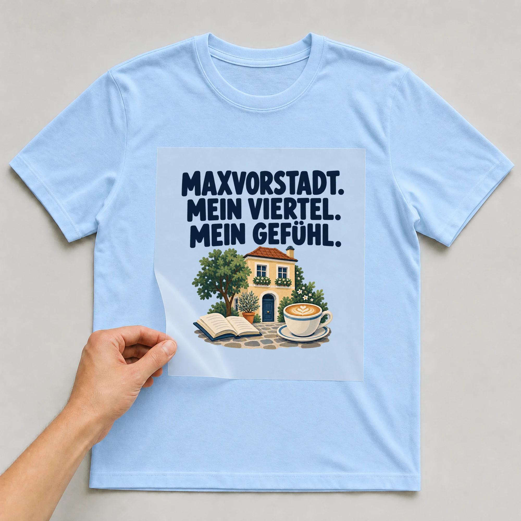 Bügelbild „MAXVORSTADT. MEIN VIERTEL. MEIN GEFÜHL.“ auf babyblauem T-Shirt, Folie wird aufgelegt