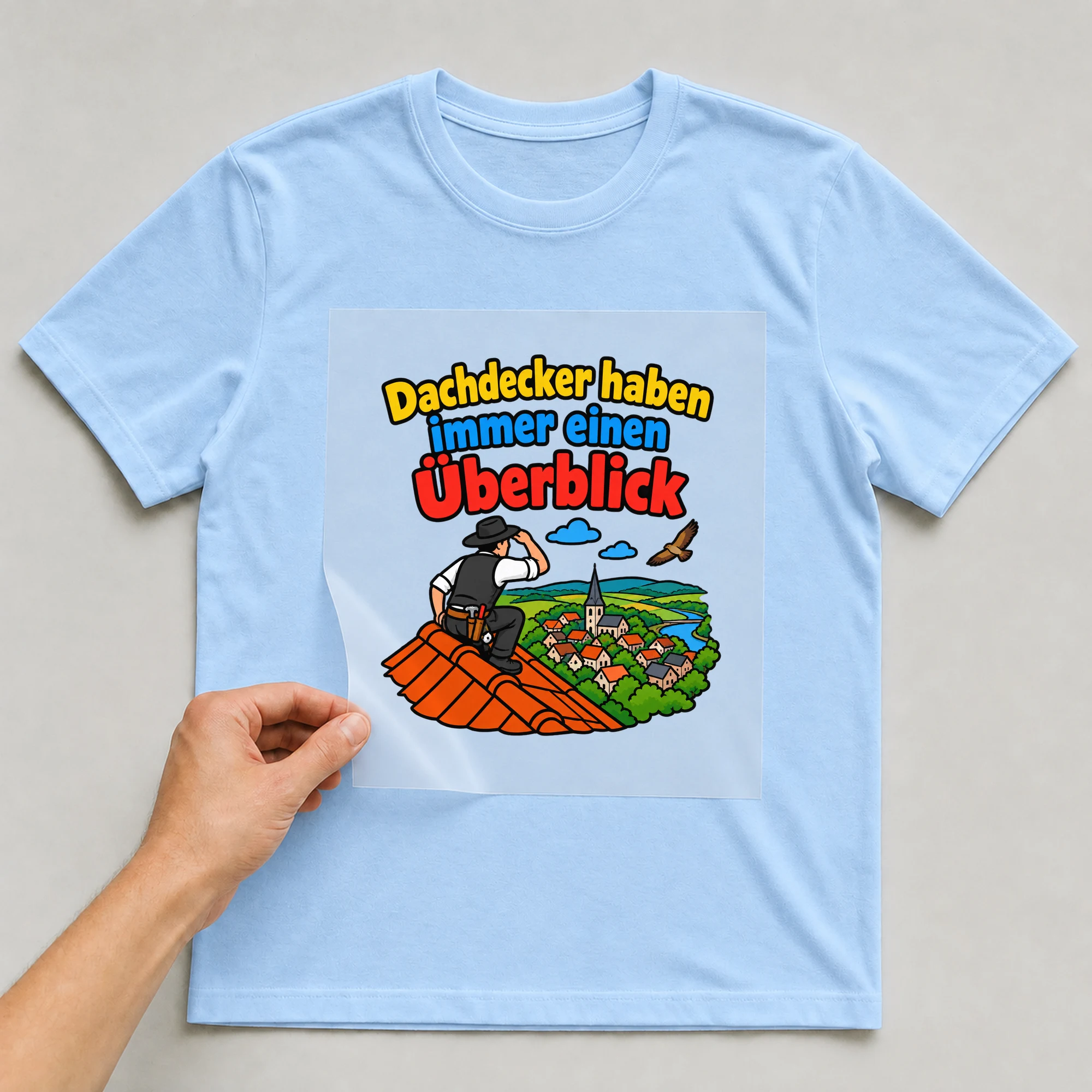 Bügelbild „Dachdecker haben immer einen Überblick“ auf babyblauem T-Shirt, Folie wird aufgelegt