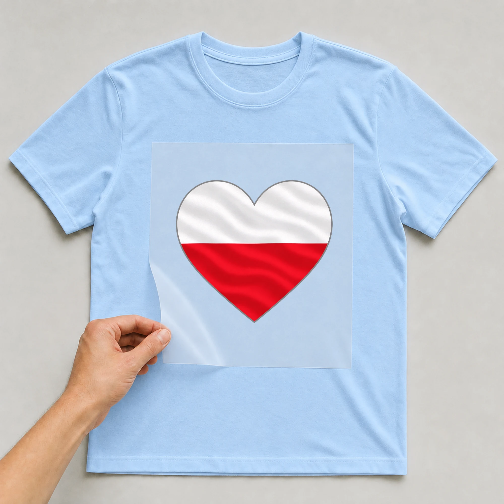 Bügelbild „Herz-Flagge Polen“ auf babyblauem T-Shirt, Folie wird aufgelegt