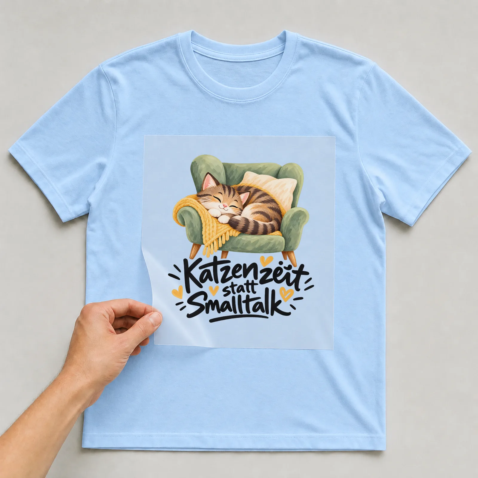 Bügelbild „Katzenzeit statt Smalltalk“ auf hellblauem T-Shirt, Folie wird aufgelegt