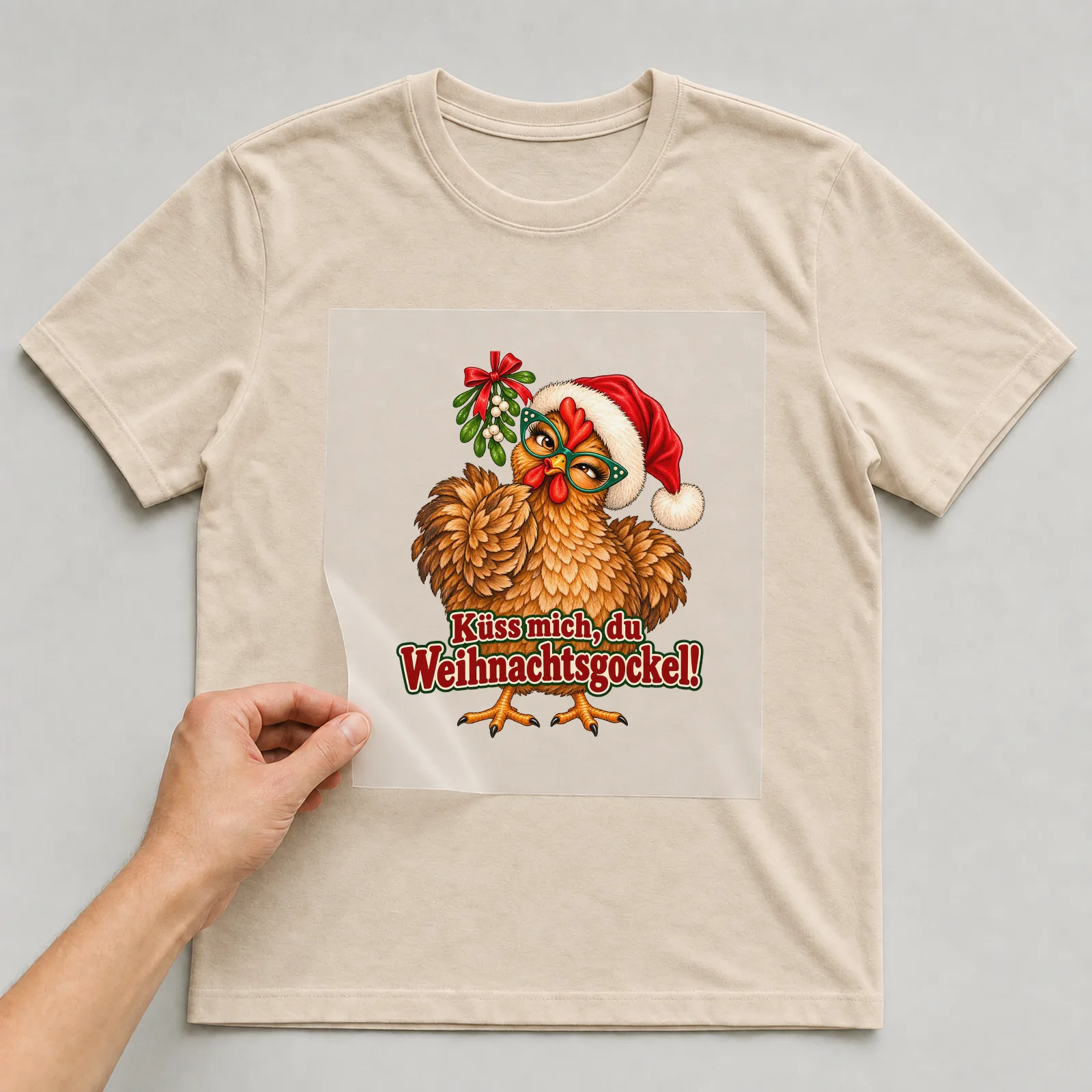 Bügelbild huhn mistelzweig auf beigem T-Shirt, Folie wird aufgelegt