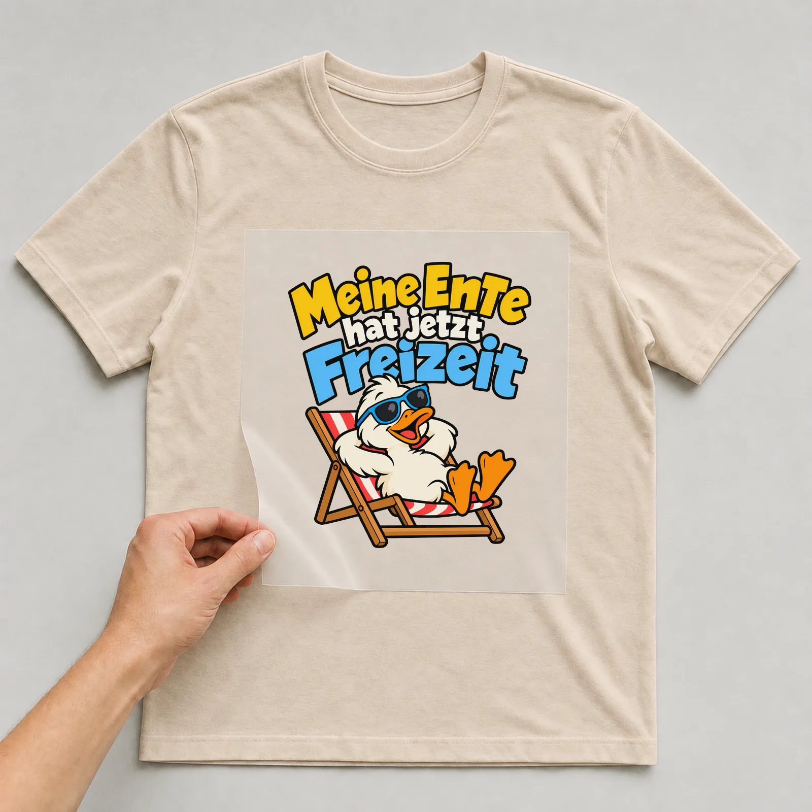 Bügelbild „Meine Ente hat jetzt Freizeit“ auf beigem T-Shirt, Folie wird aufgelegt