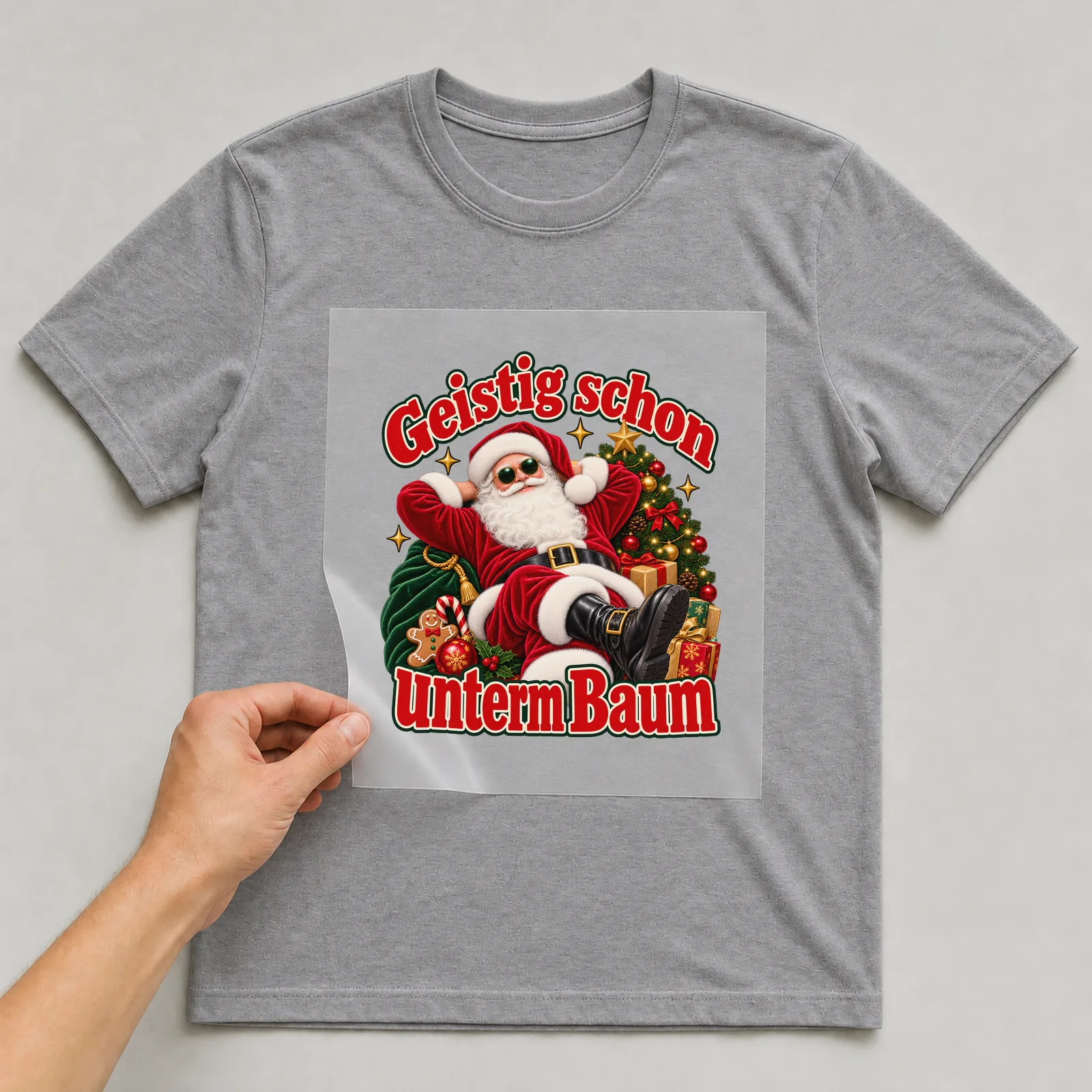 Bügelbild Geistig schon unterm Baum (Freche Weihnachtsklassiker) auf grauem T-Shirt, Folie wird aufgelegt