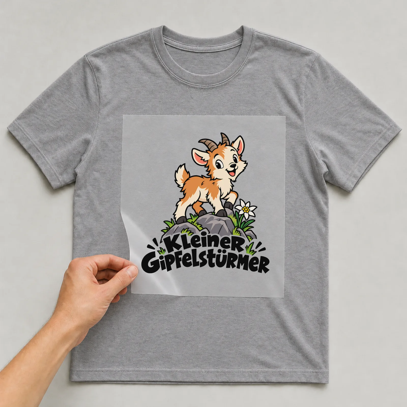 Bügelbild „Kleiner Gipfelstürmer“ auf grauem T-Shirt, Folie wird aufgelegt